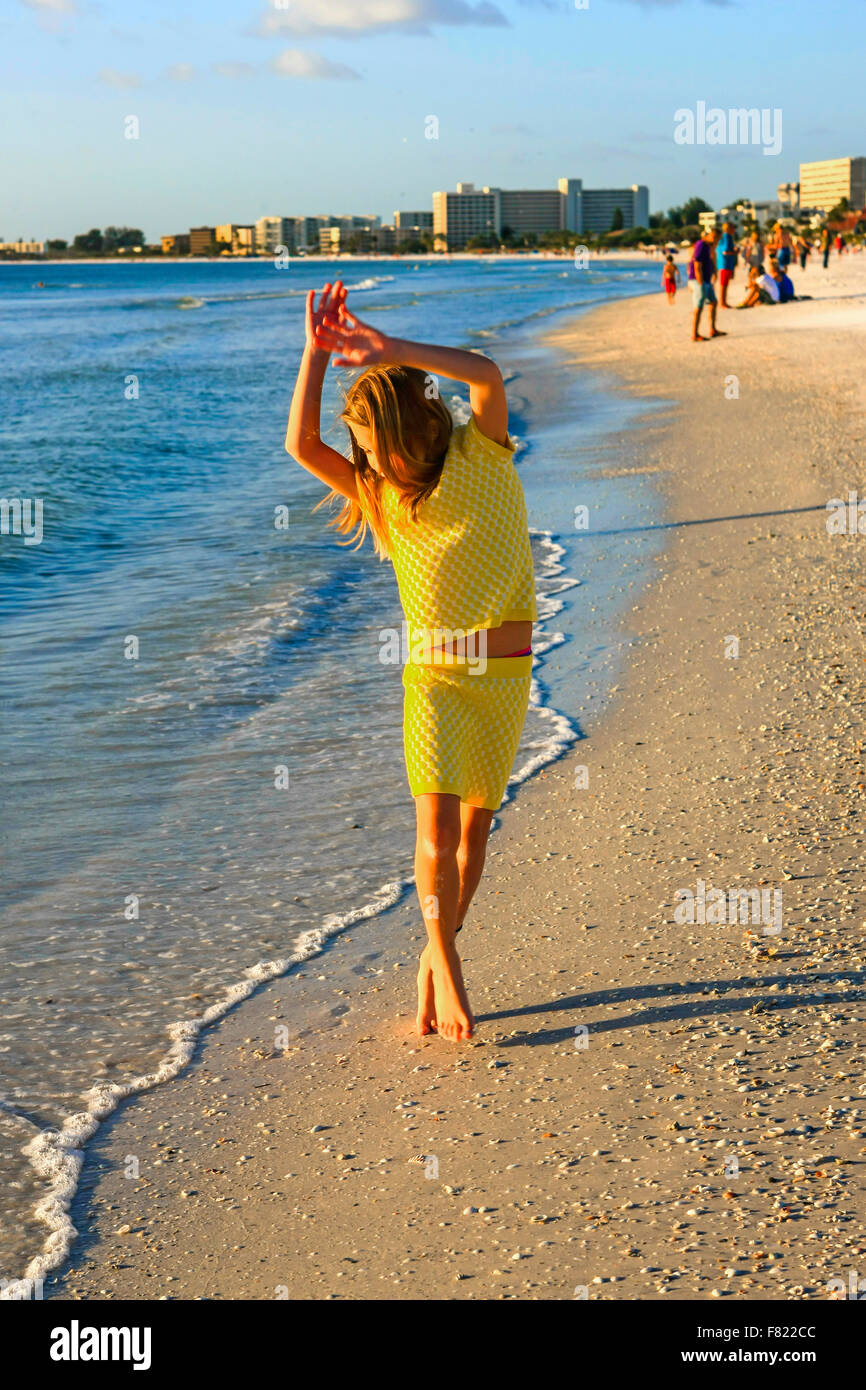 Young preteen girl dancing at sunset on the beach at Siesta Key