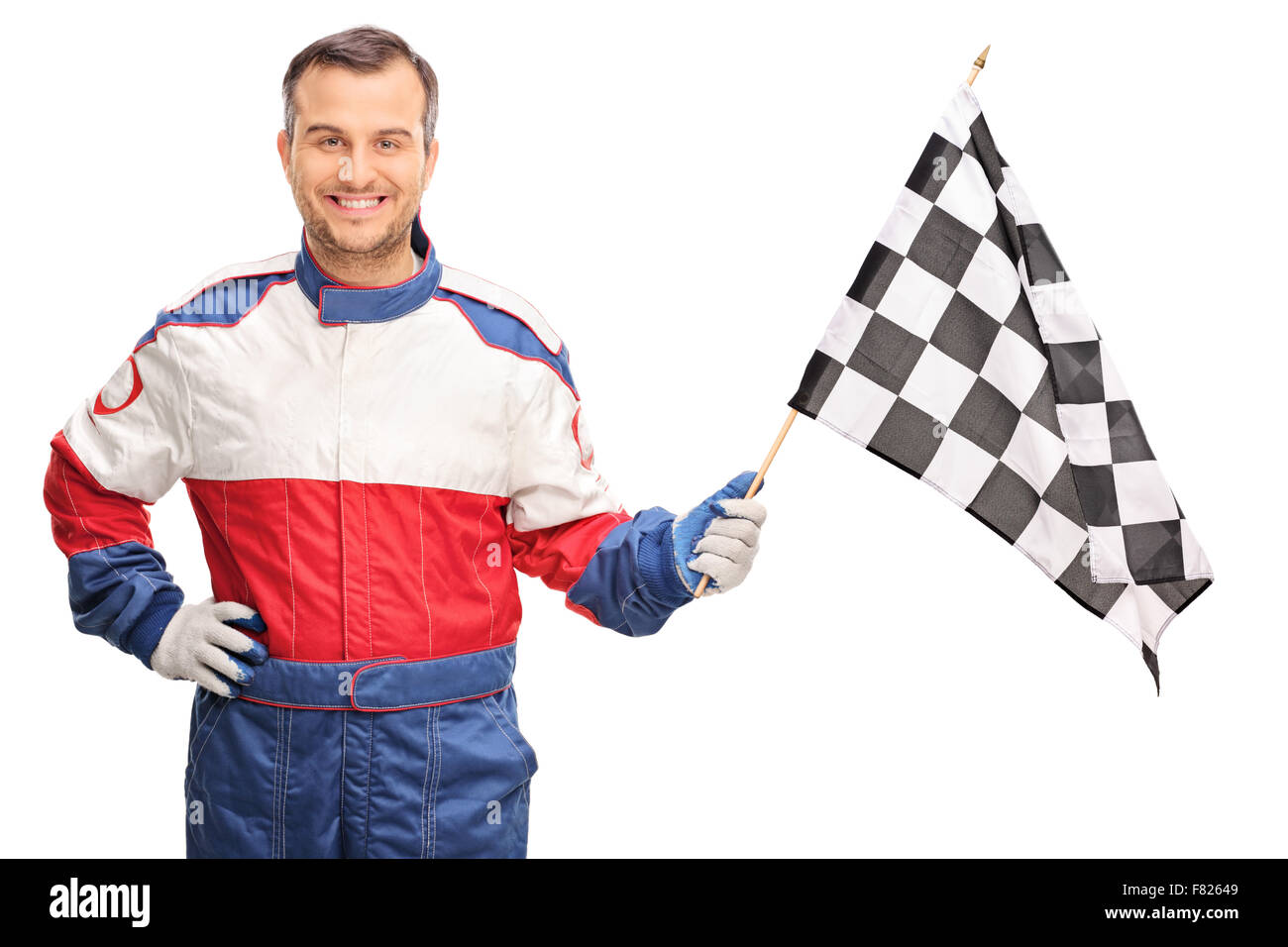 Young man in a racing suit waving a checkered race flag and looking at the camera isolated on white background Stock Photo