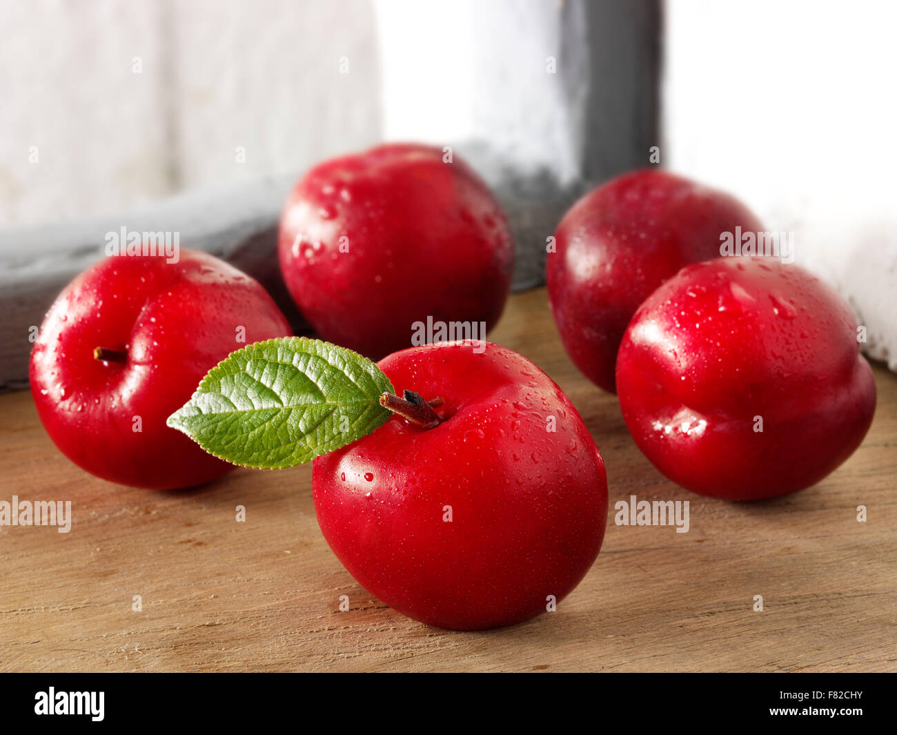 Fresh whole uncooked red Victoria plums in a rustic kitchen Stock Photo