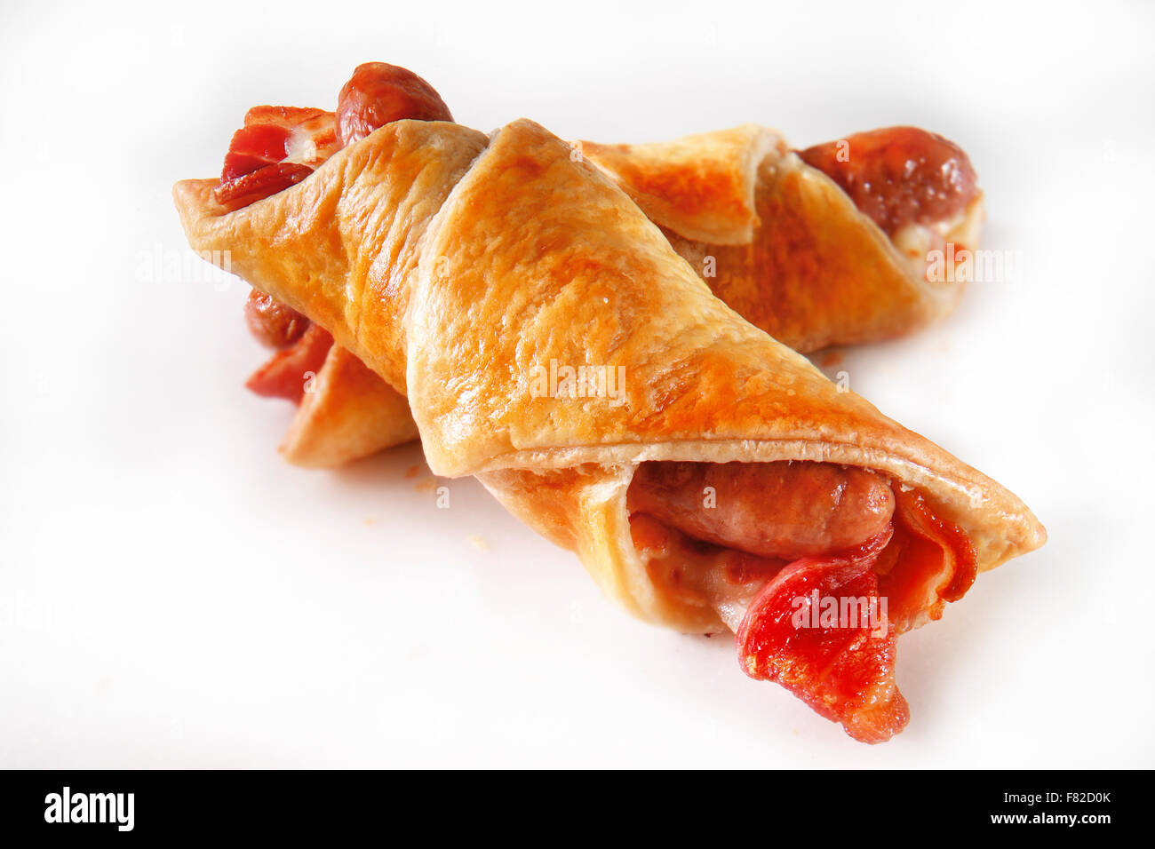 Sausauge & Bacon in puff pastry pastry roll snack against a white background Stock Photo