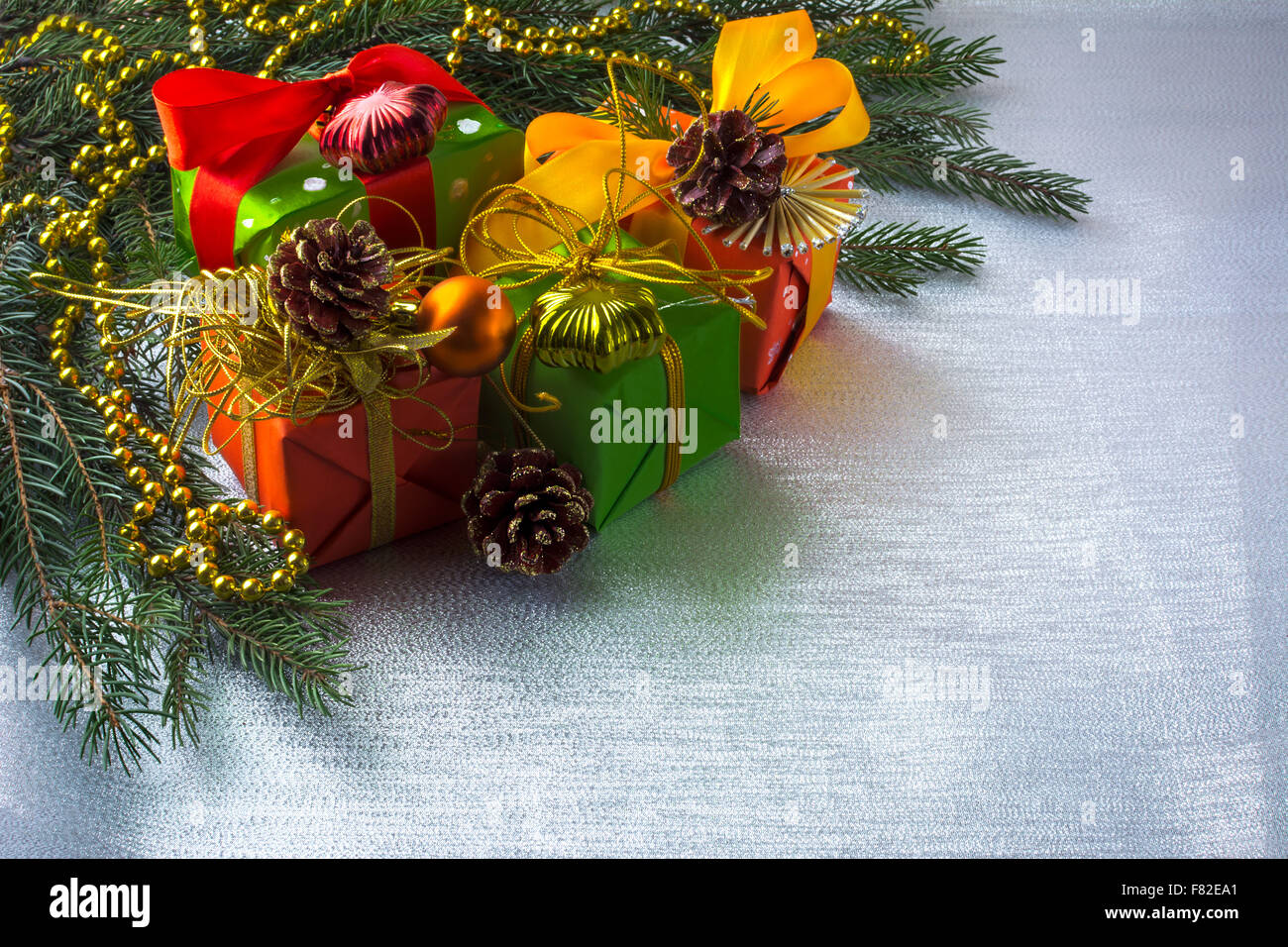 Christmas decoration with fir branches, gift boxes, ribbon, balls, ornament on silver sparkles background, selective focus Stock Photo
