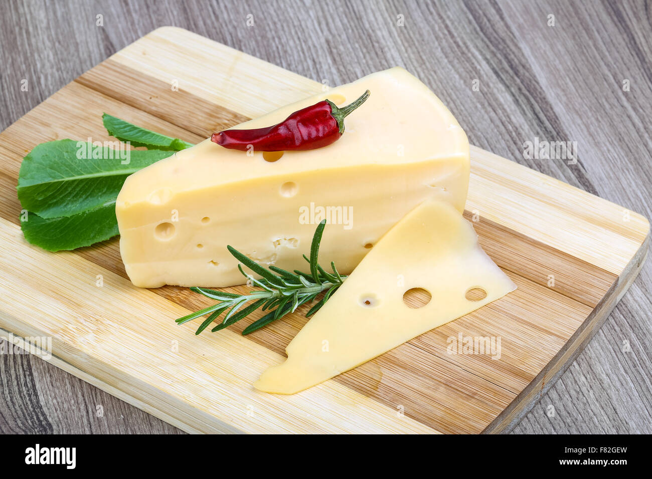 Triangle Pepper Triangle yellow cheese with rosemary, pepper and salad leaves Stock ...