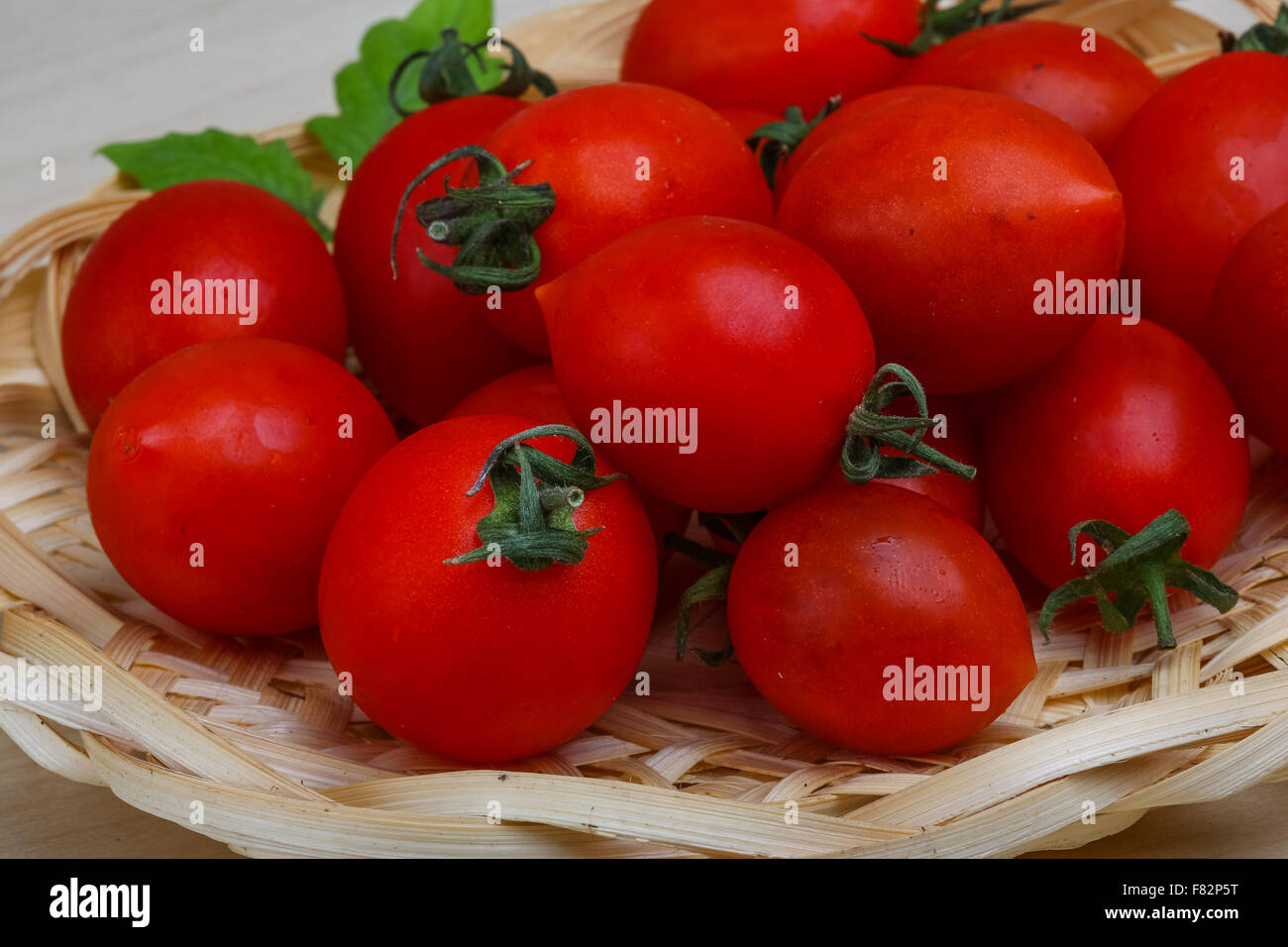 Cherry tomatoes in the basket with fresh green leaf Stock Photo - Alamy