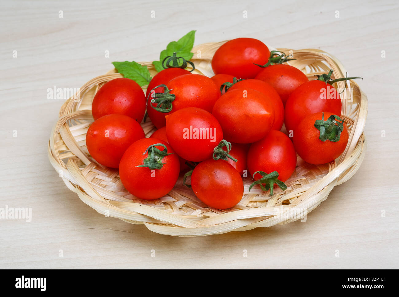 Cherry tomatoes in the basket with fresh green leaf Stock Photo - Alamy