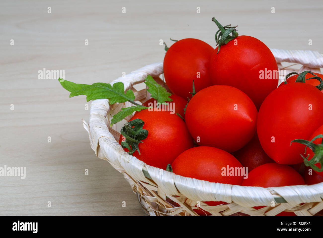 Cherry tomatoes in the basket with fresh green leaf Stock Photo - Alamy