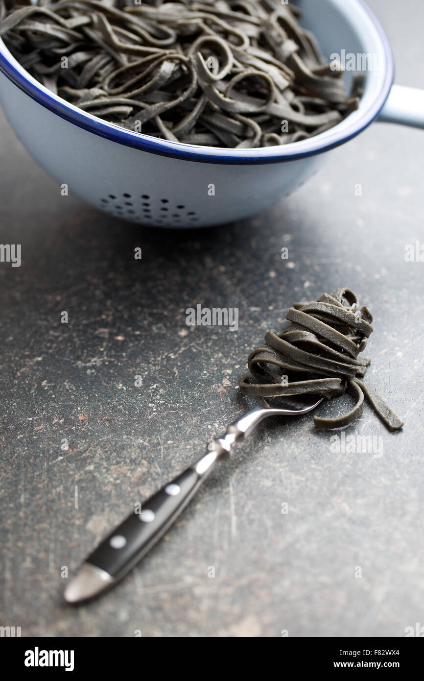 cooked black noodles with squid sepia ink on fork Stock Photo