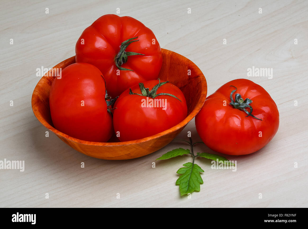 Red tomatoes in the basket with green branch Stock Photo - Alamy