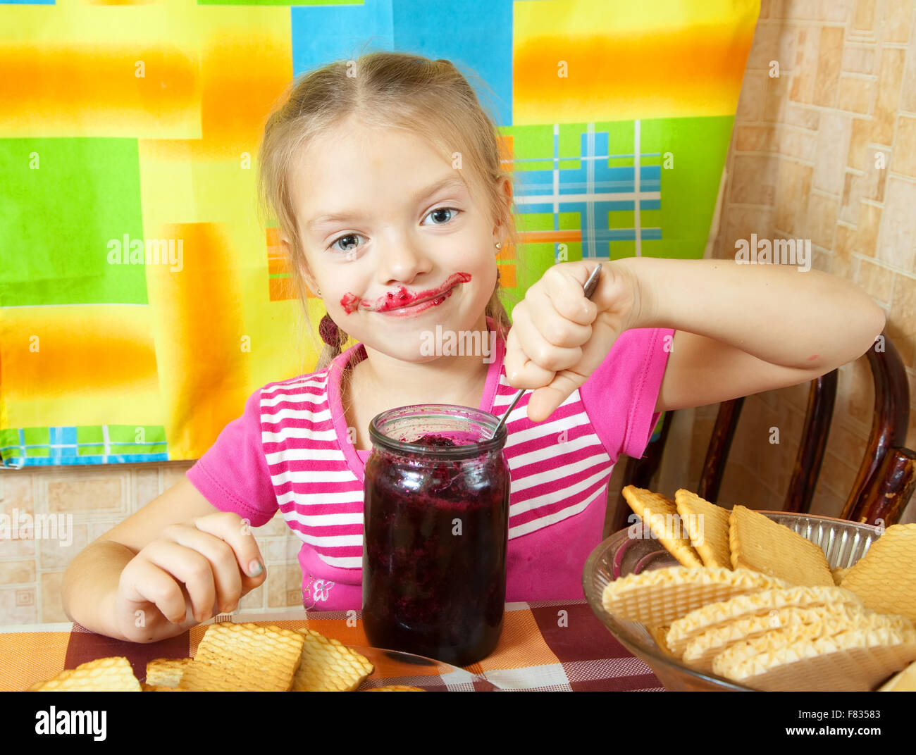 Little girl eating marmalade from glass jar at kitchen Stock Photo Alamy