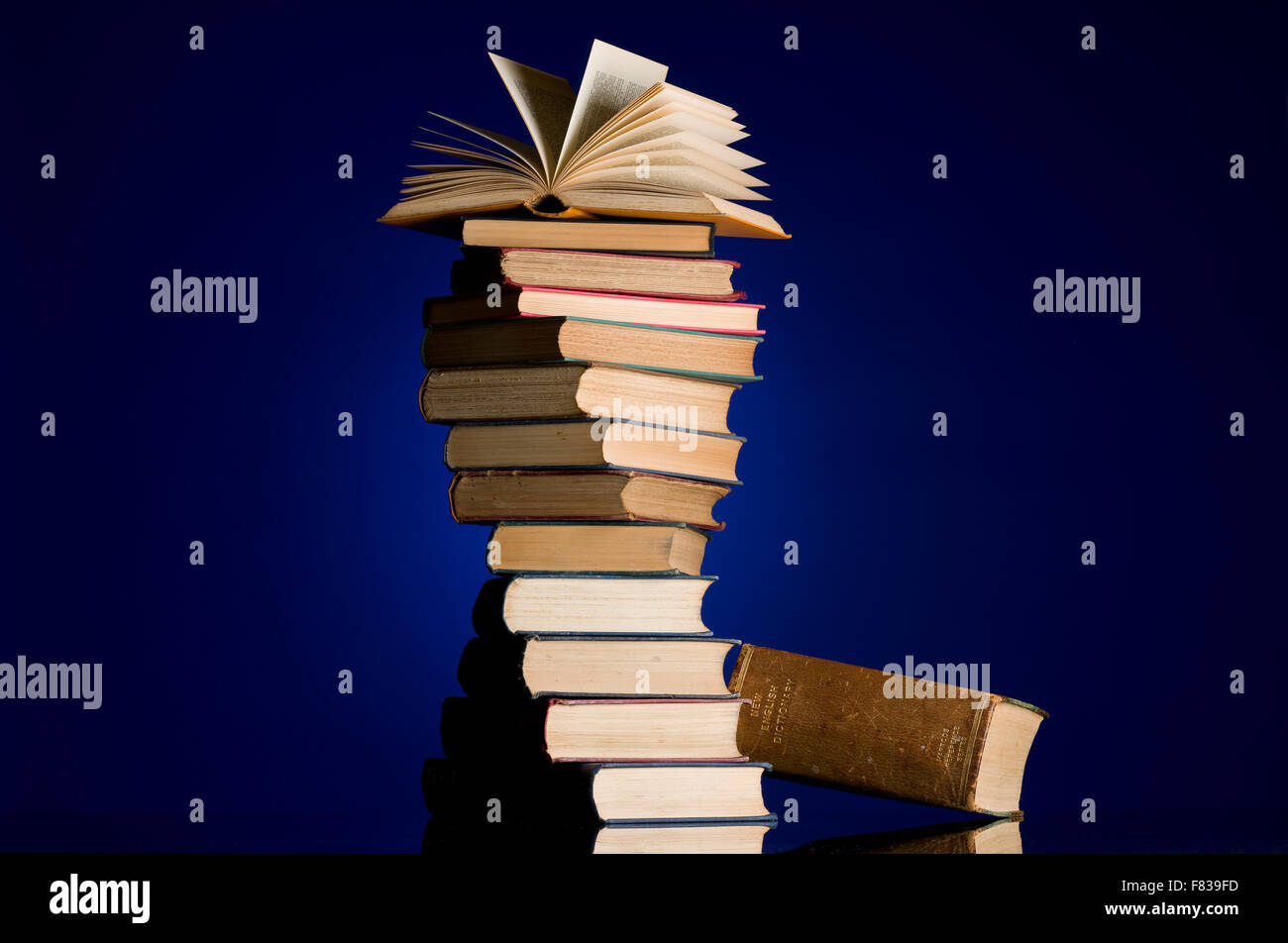 Pile of old books in a spiral twist. Open book at the top of the pile. Book collection. Read