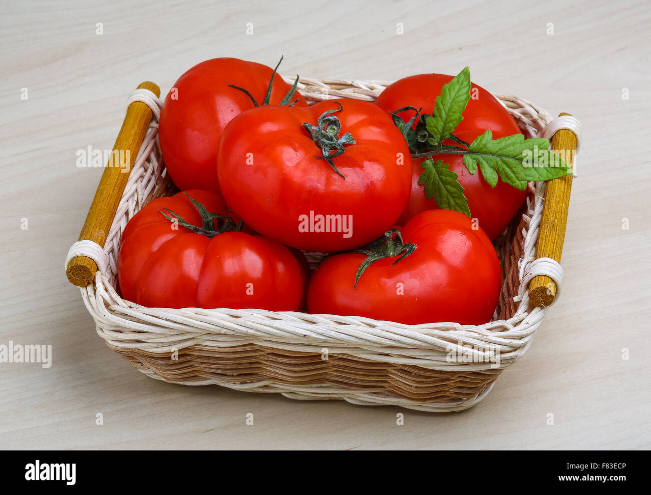Red tomatoes in the basket with green branch Stock Photo - Alamy