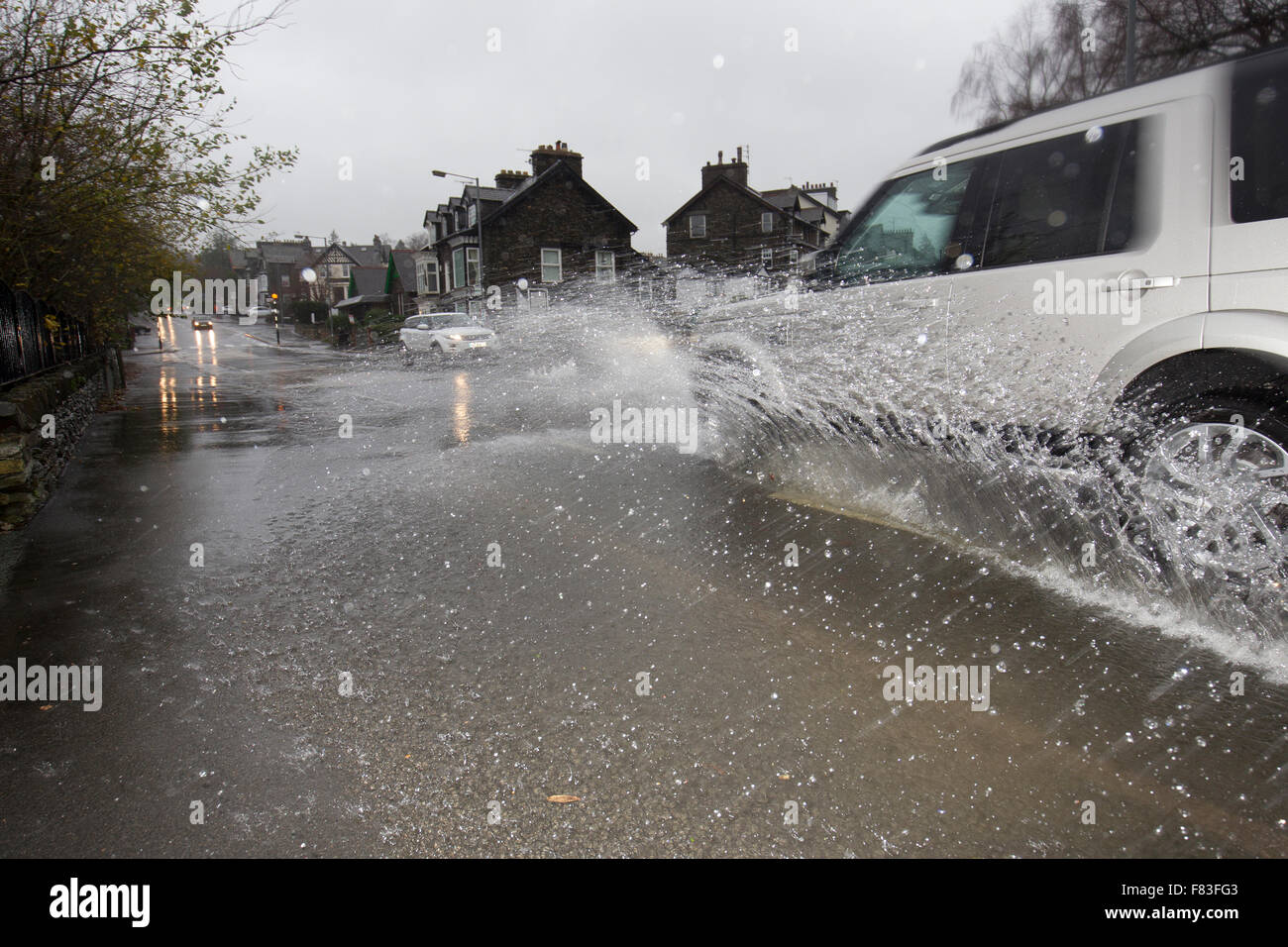 Cumbria 5th December 2015 UK Weather The Met Office issues its highest red warning for north-west England, urging against all non-essential travel.Lake Windermer &at Bowness on Windermere Buisenesss prepair for flooding Cars going through flooding - Bowness on Windermere village Credit:  Gordon Shoosmith/Alamy Live News Stock Photo