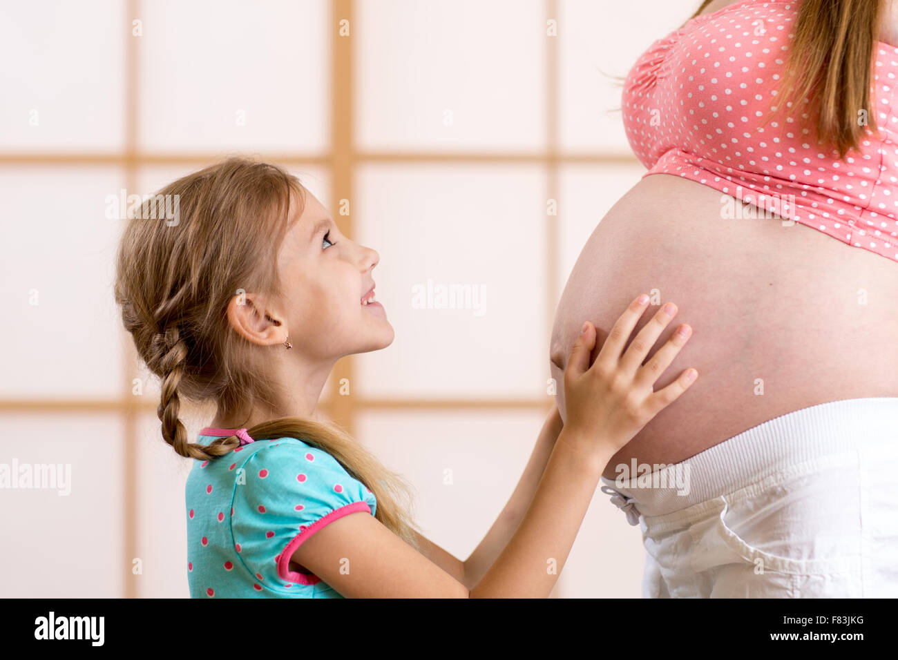 kid girl hugging and kooking at pregnant mother Stock Photo