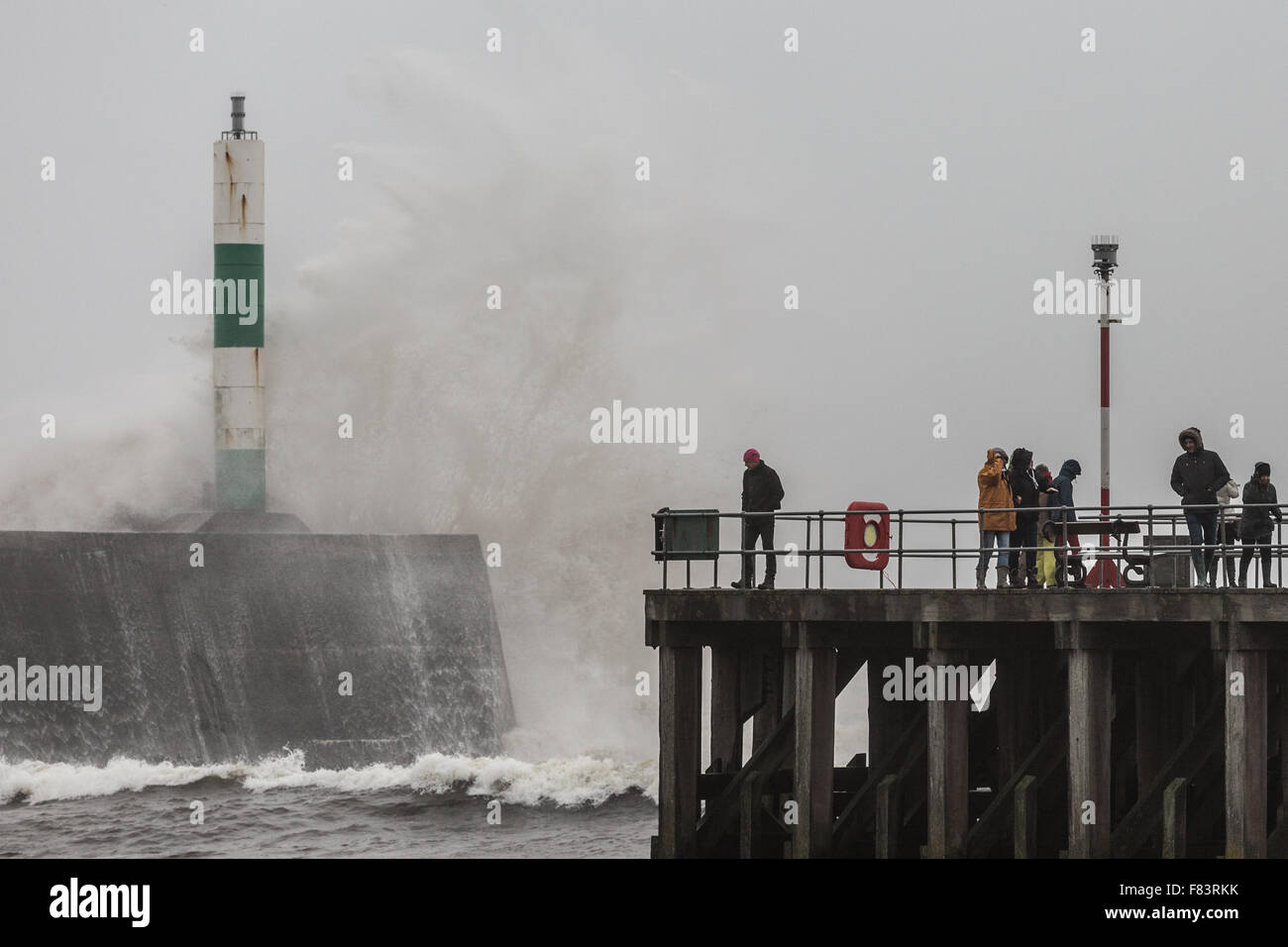 Wales, UK. 05th December 2015 Storm Desmond, the 4th named recent storms brings gale force winds and rough seas to Aberystwyth, battering the jetty near the harbour entrance as pedestrians stand watching on the west coast of Wales. Credit:  Ian Jones/Alamy Live News Stock Photo