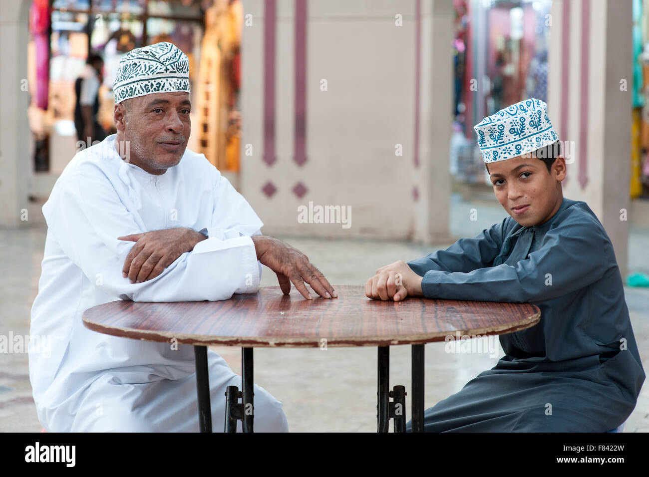 Omani man and his son sitting outside the Mutrah souk in Muscat, the capital of the Sultanate of Oman. Stock Photo