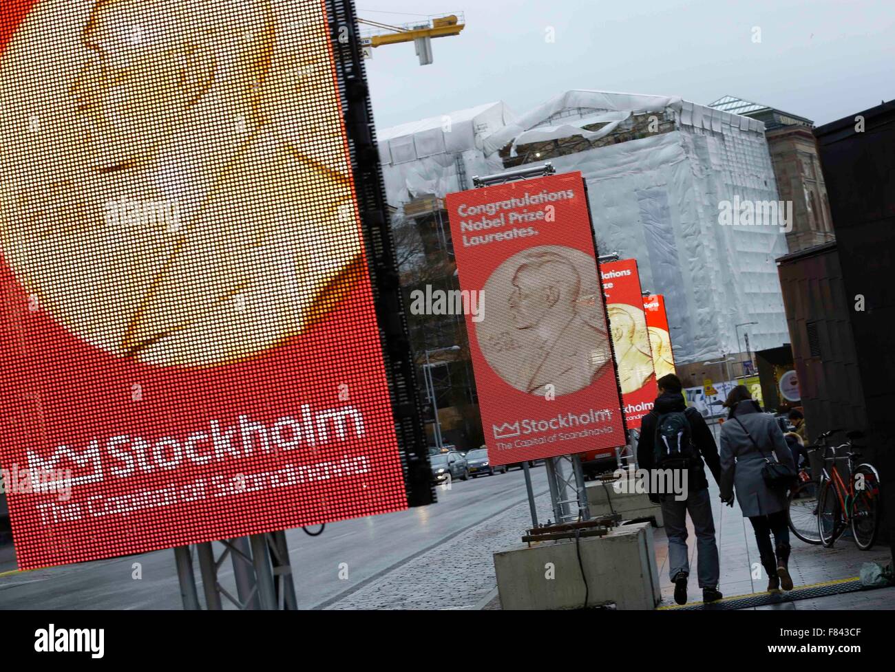 Stockholm, Dec. 5. 10th Dec, 2015. Pedestrians walk past screens with image of Nobel Prize medal in downtown Stockholm, capital of Sweden, Dec. 5, 2015. The 2015 Nobel Prize awarding ceremony will be held here on Dec. 10, 2015. © Ye Pingfan/Xinhua/Alamy Live News Stock Photo