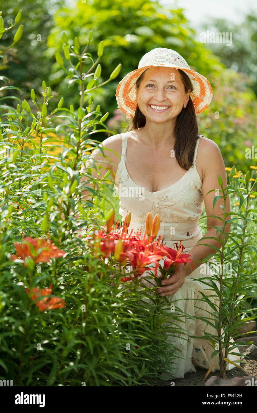 Happy mature woman in lily plant at garden Stock Photo - Alamy