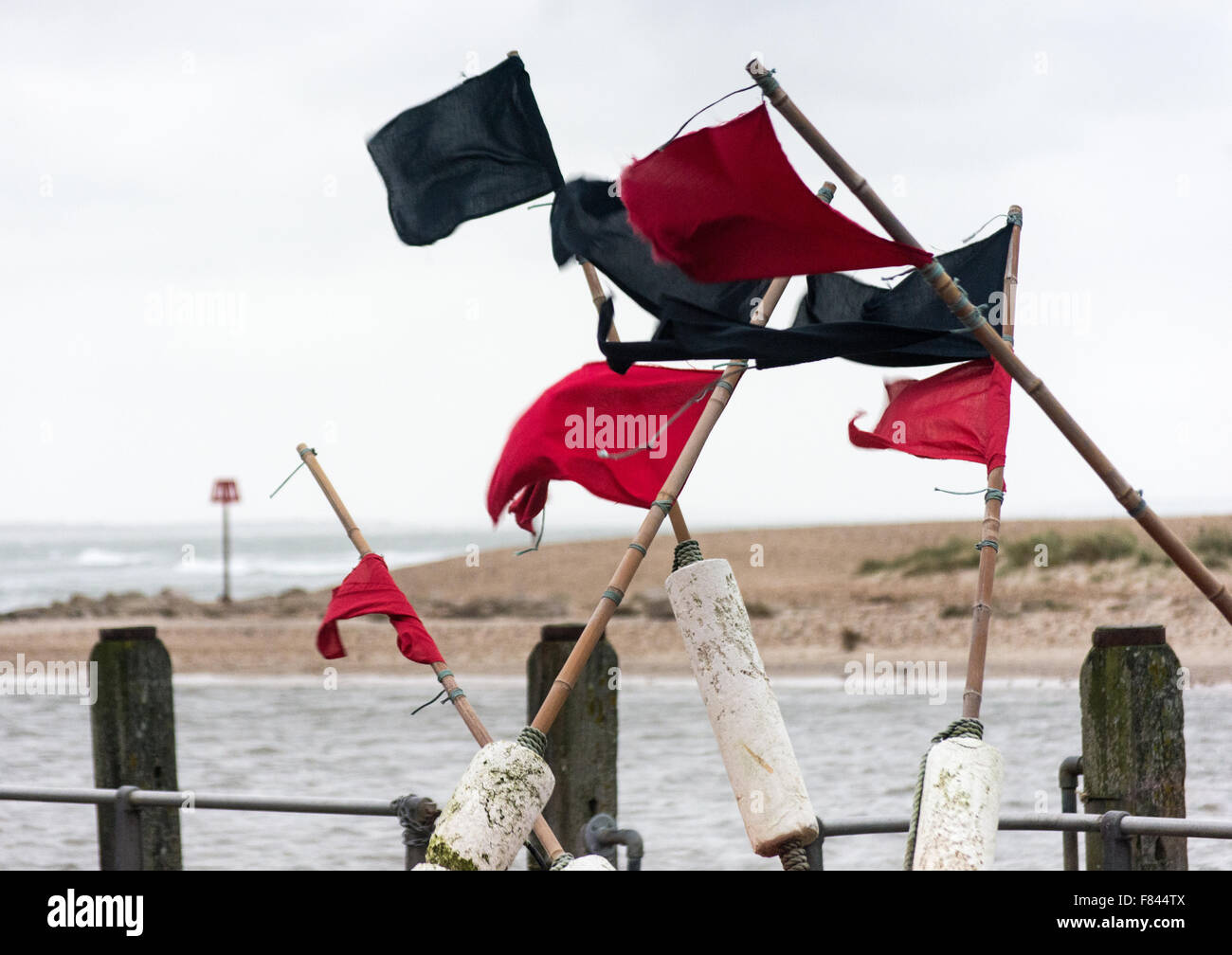 Lobster pot marker red and black flags blowing in a strong wind on the quayside at Mudeford, Dorset, UK Stock Photo