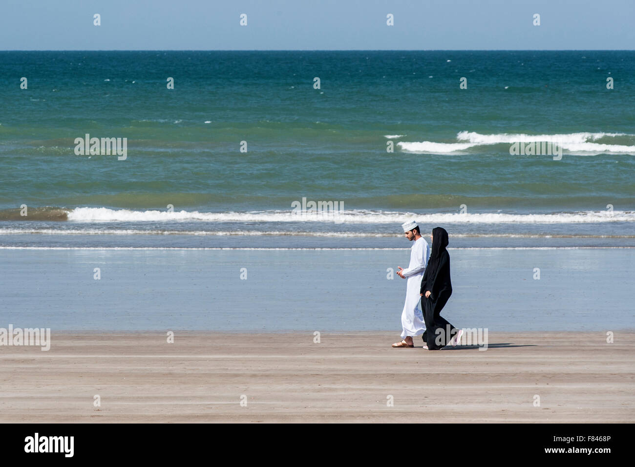 Omani couple walking on Qurum beach in Muscat, the capital of the Sultanate of Oman. Stock Photo