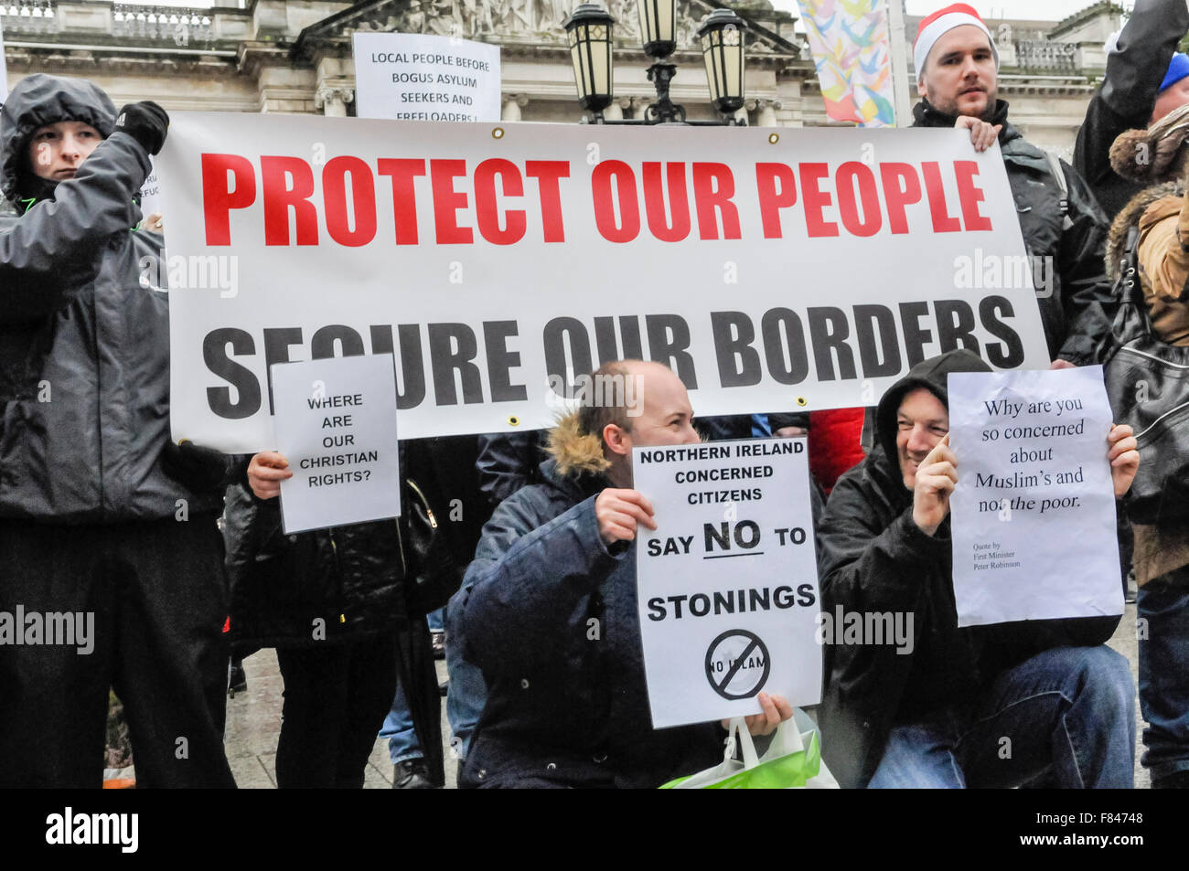 Belfast, Northern Ireland. 05 Dec 2015 - People hold up anti-refugee posters, including the message 'Protect our people. Secure our borders' and 'Say no to stonings' as the Protestant Coalition hold a protest against Islamic refugees coming to Northern Ireland. Credit:  Stephen Barnes/Alamy Live News Stock Photo