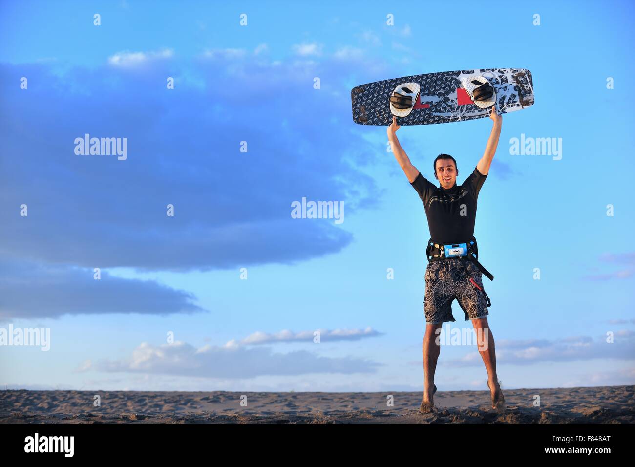 Portrait of a strong young surf man at beach on sunset in a