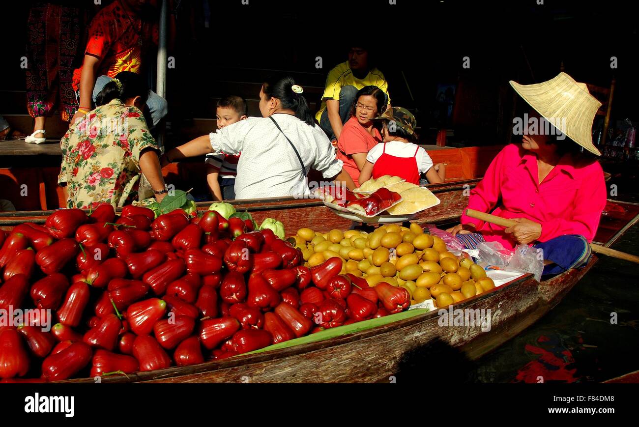 Samut Songkhram, Thailand:   Woman selling fresh fruits from her boat as she paddles along a canal at the floating market * Stock Photo