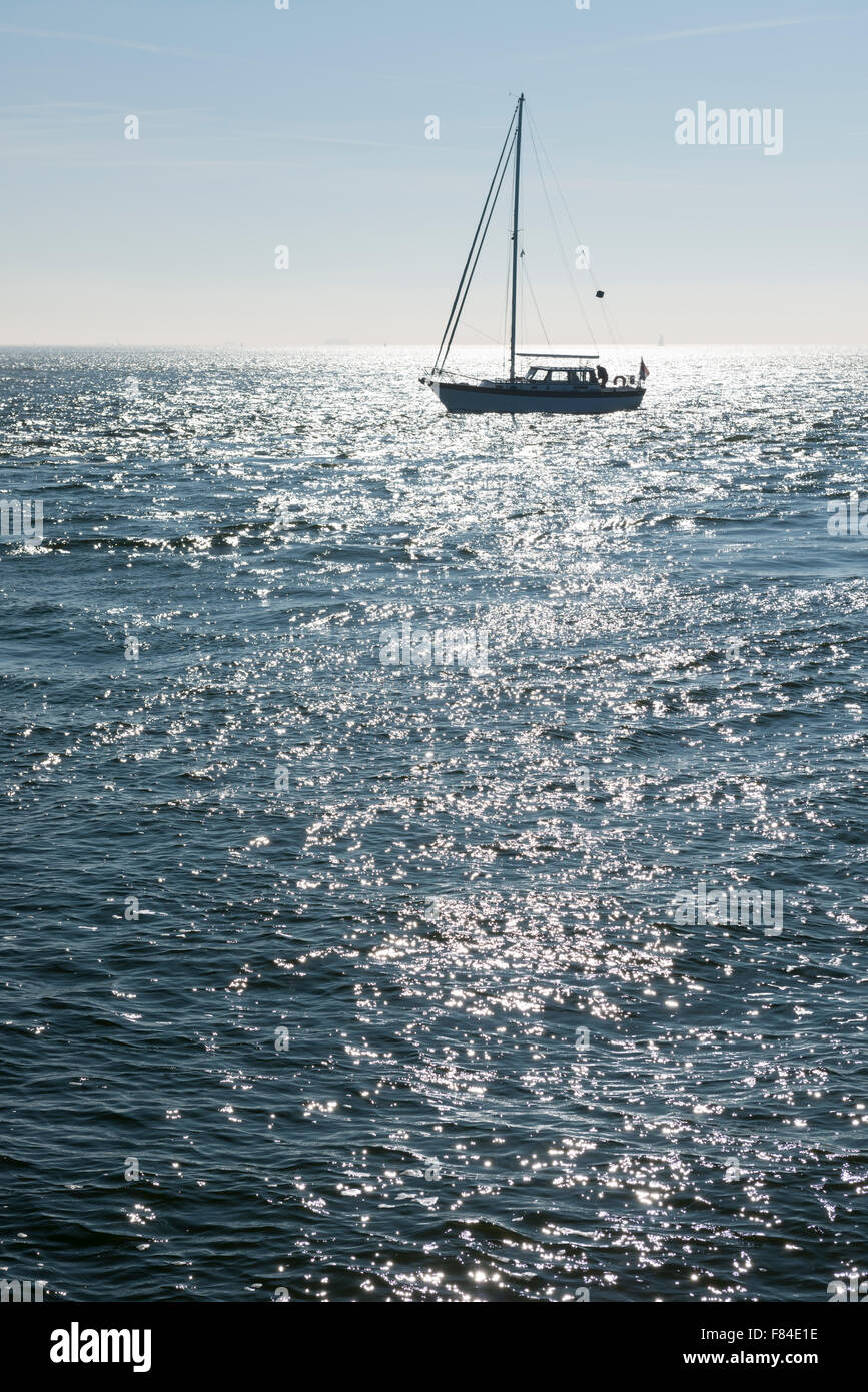 Sailing boat against the glare of the Sun in the sea Stock Photo