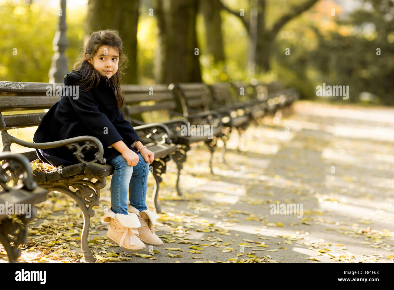 Little girl on the bench in the autumn park Stock Photo - Alamy