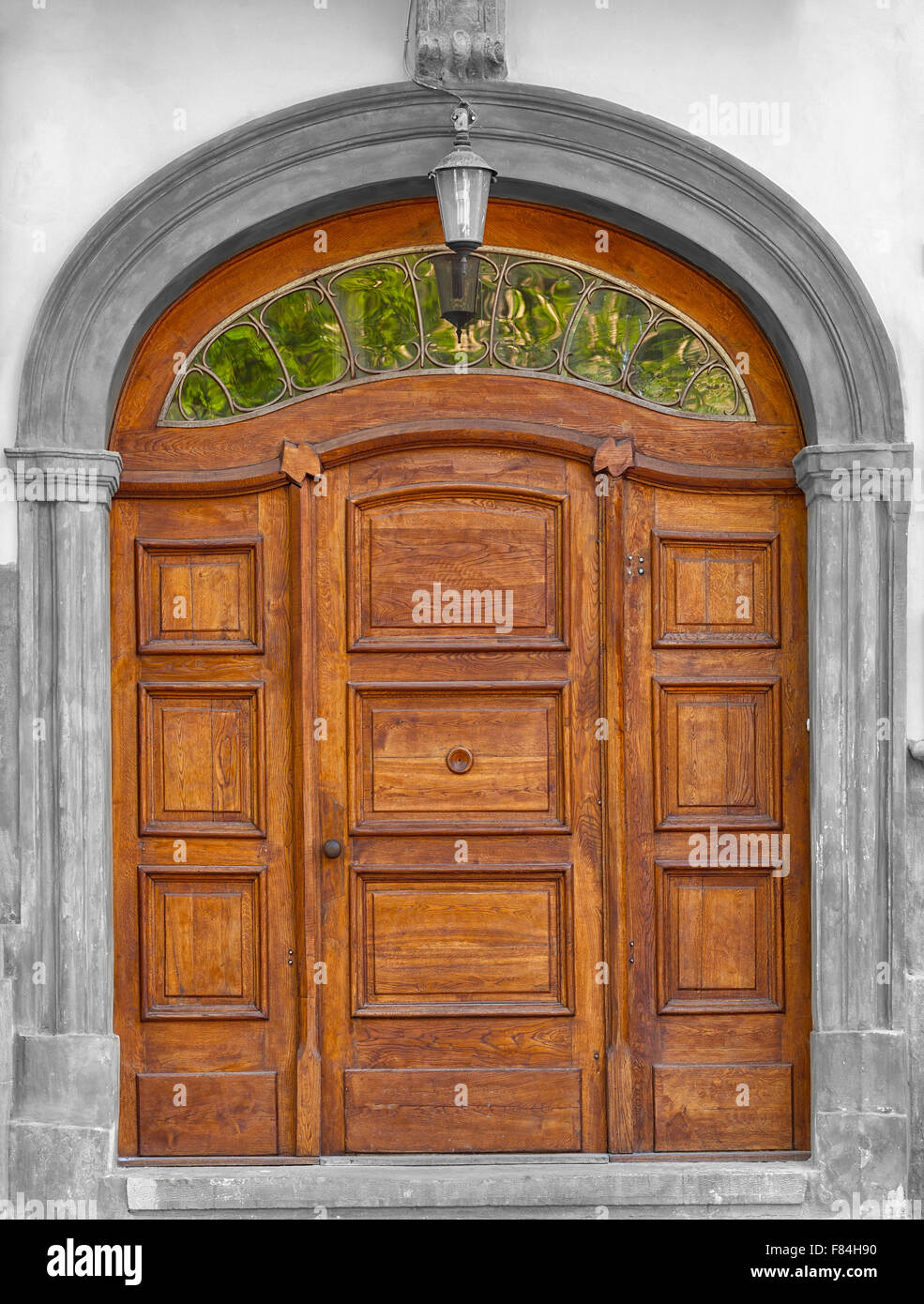 Traditional arched timber door with lead light glass above. Stock Photo