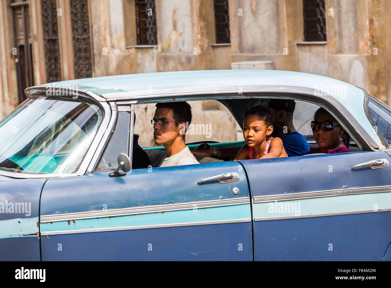 Locals sun drenched in an old timer on the streets of Havana. Stock Photo