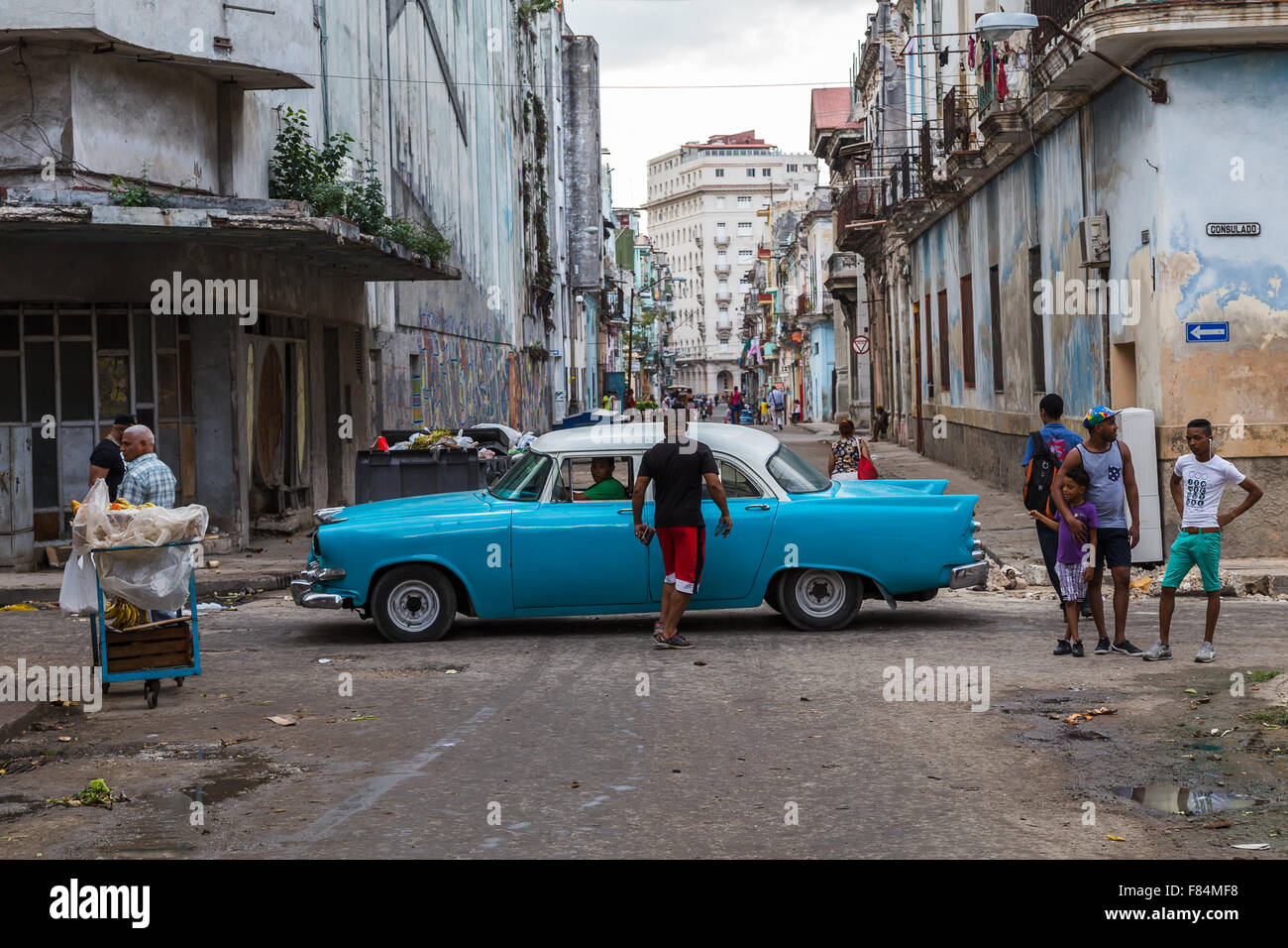 Looking over Calle Consulado in Cento Havana, Cuba as a classical car passes some locals on the streets. Stock Photo