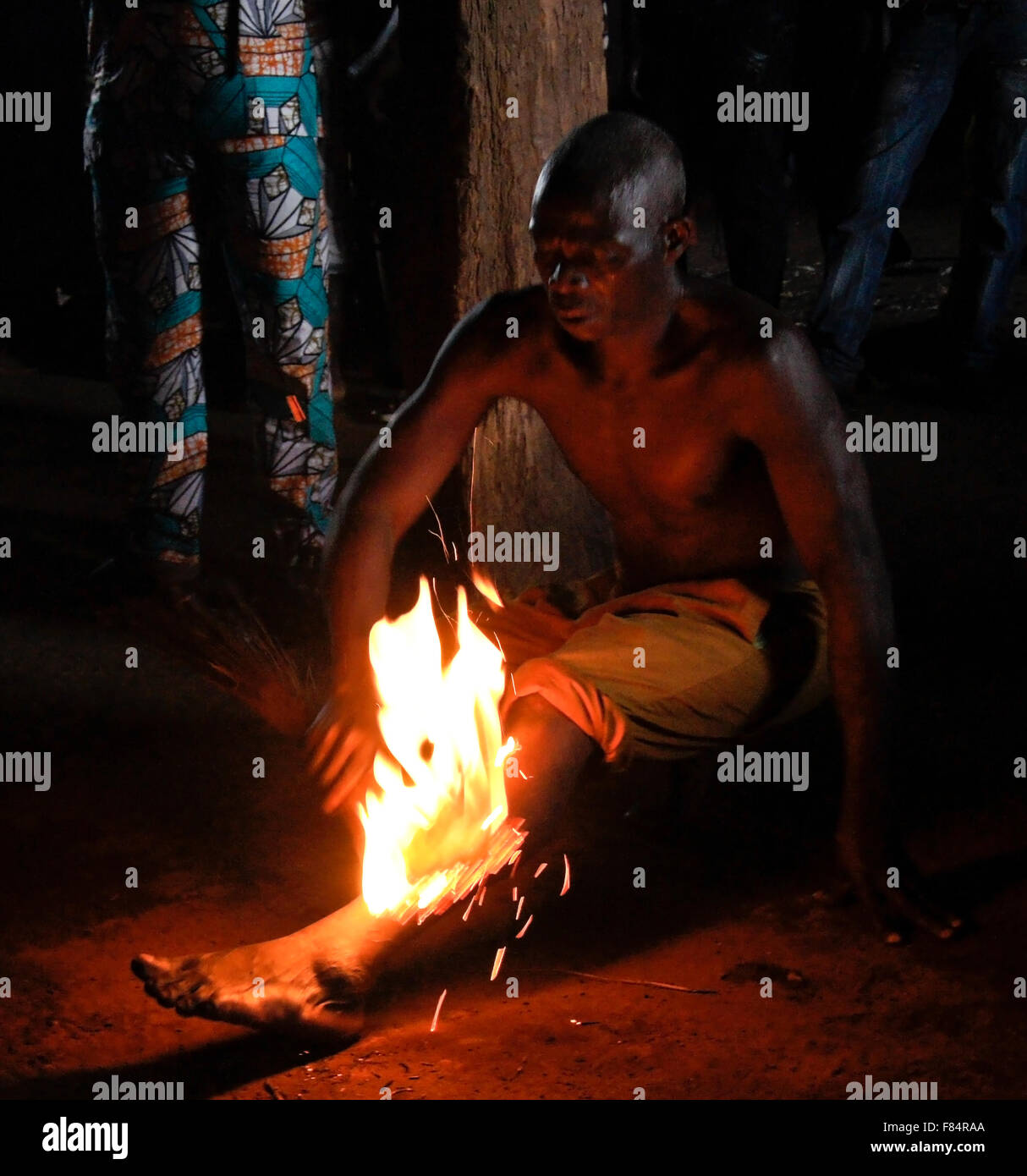 Man passing fire over leg at Bassare T'Bol fire dance, Sokodé, Togo Stock Photo