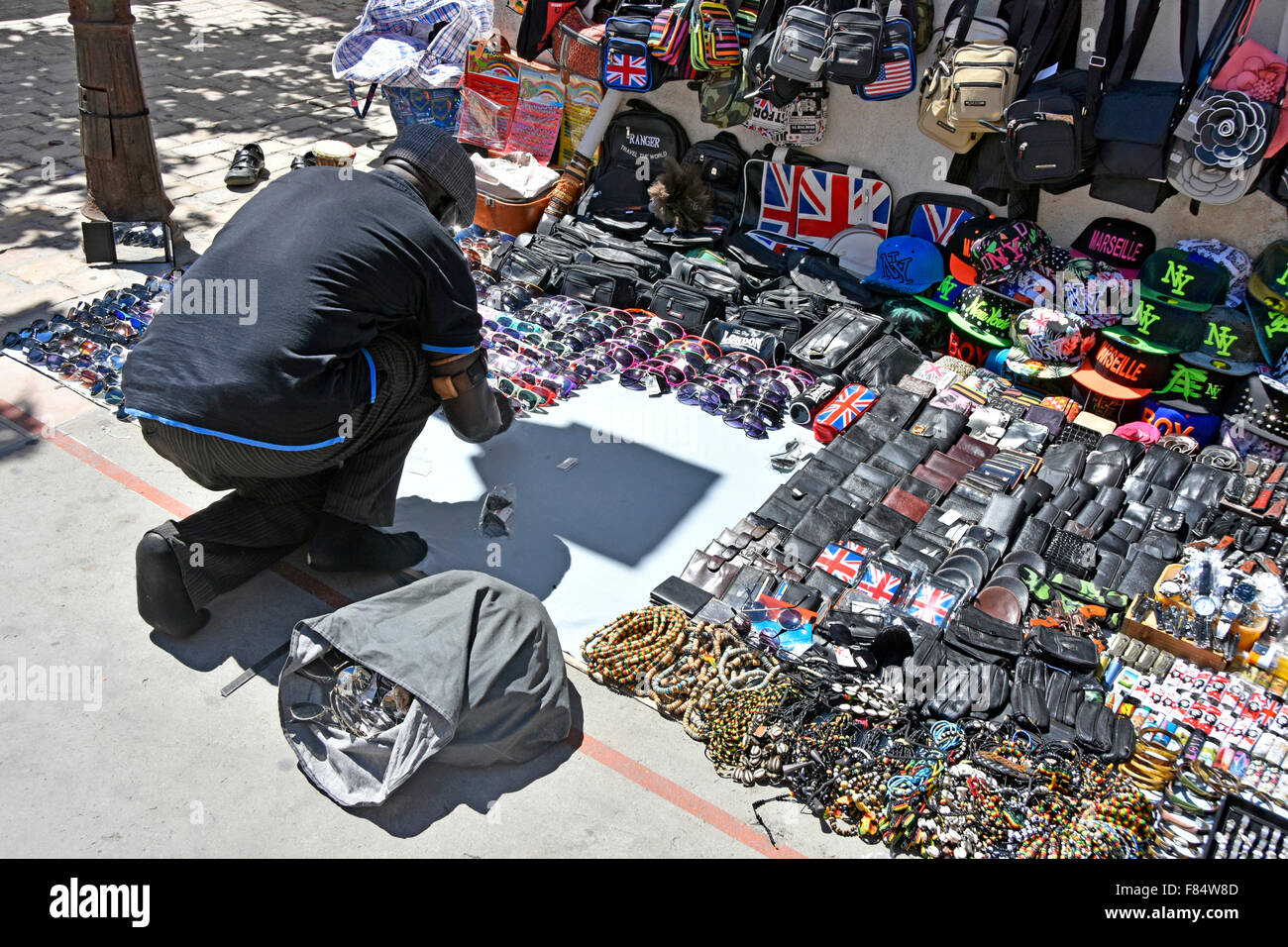 Black man lays out his wares in a shopping street in the Mediterranean seaside resort town of Saintes Maries de la Mer Stock Photo