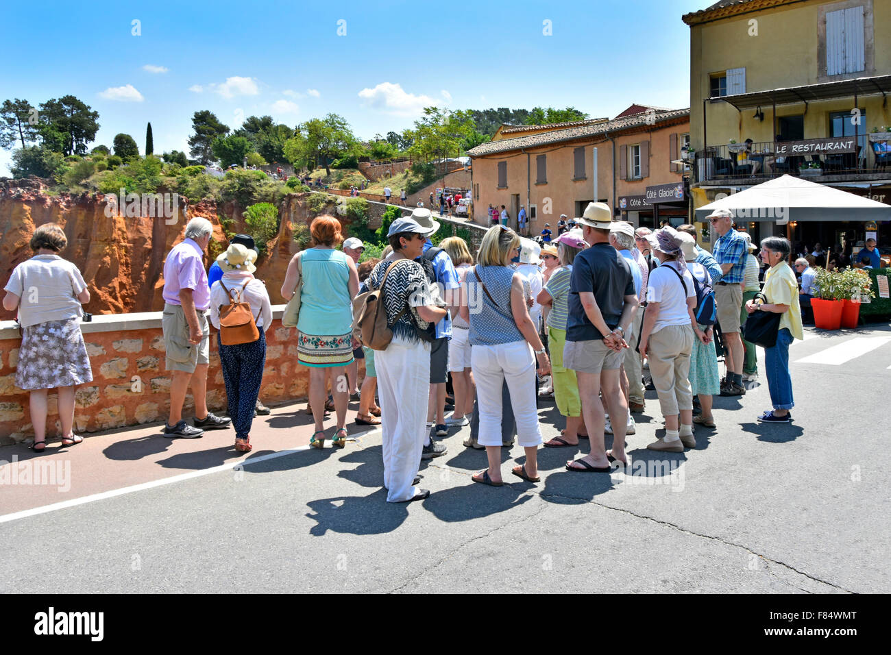 Roussillon Provence village Vaucluse France hilltop village group of people in tourist coach party gathered around tour guide (hidden) Stock Photo