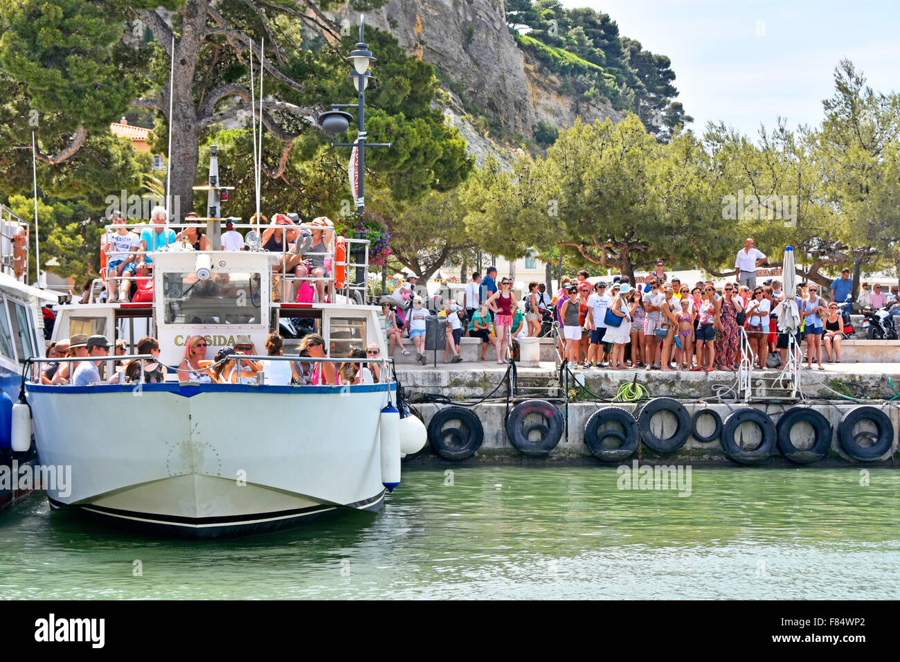 Cassis France Provence crowded harbour tourist boat awaiting departure trip to Calanque coves crowd of people waiting for next boat wall tyre buffers Stock Photo