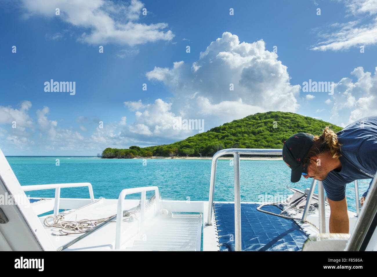 A crew member prepares to anchor a charter boat at Buck Island seen ahead in the Caribbean near St. Croix, U.S. Virgin Islands. USVI, U.S.V.I. Stock Photo