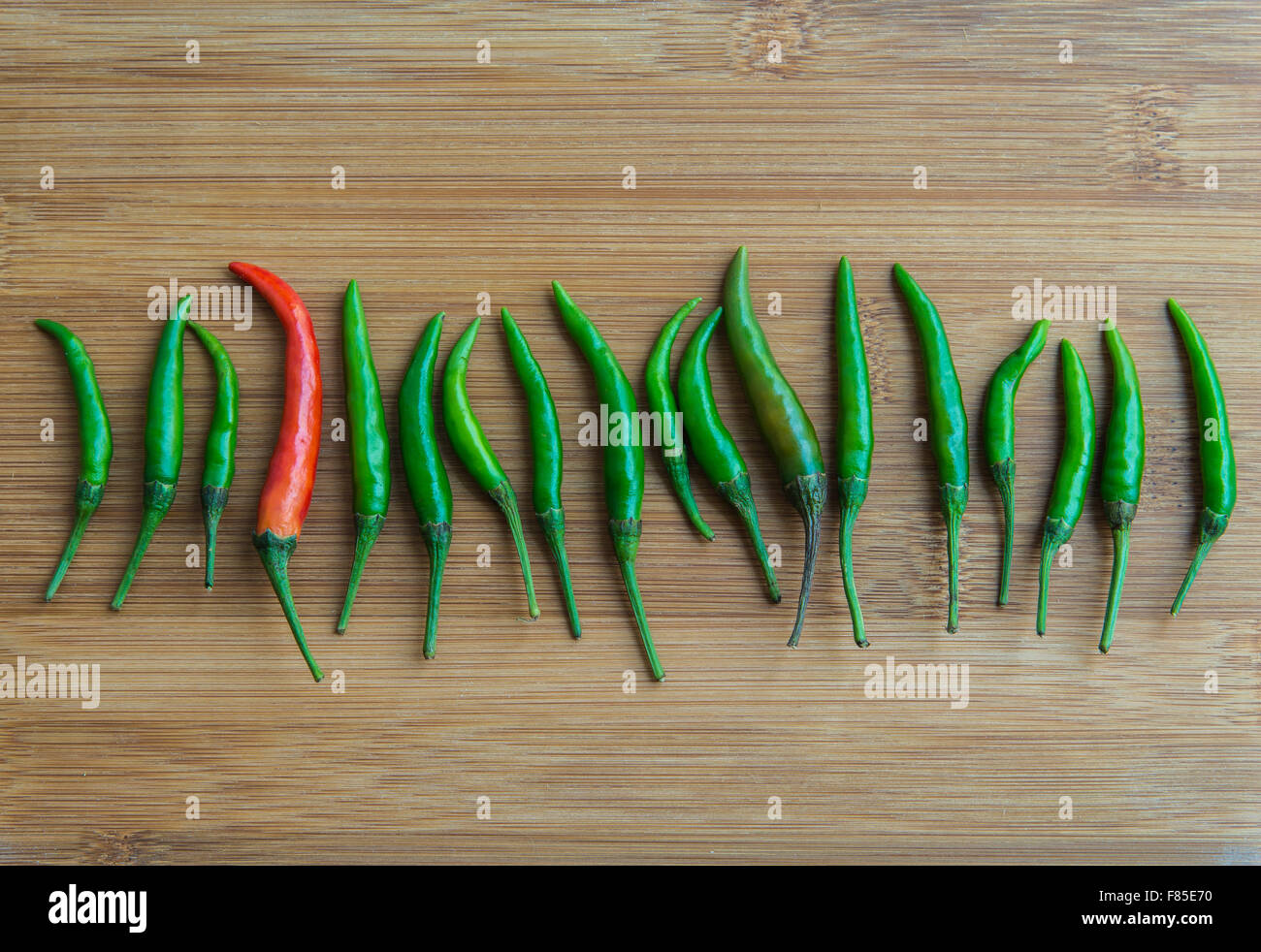 A red chilli pepper in Green chilli pepper on chopping block Stock