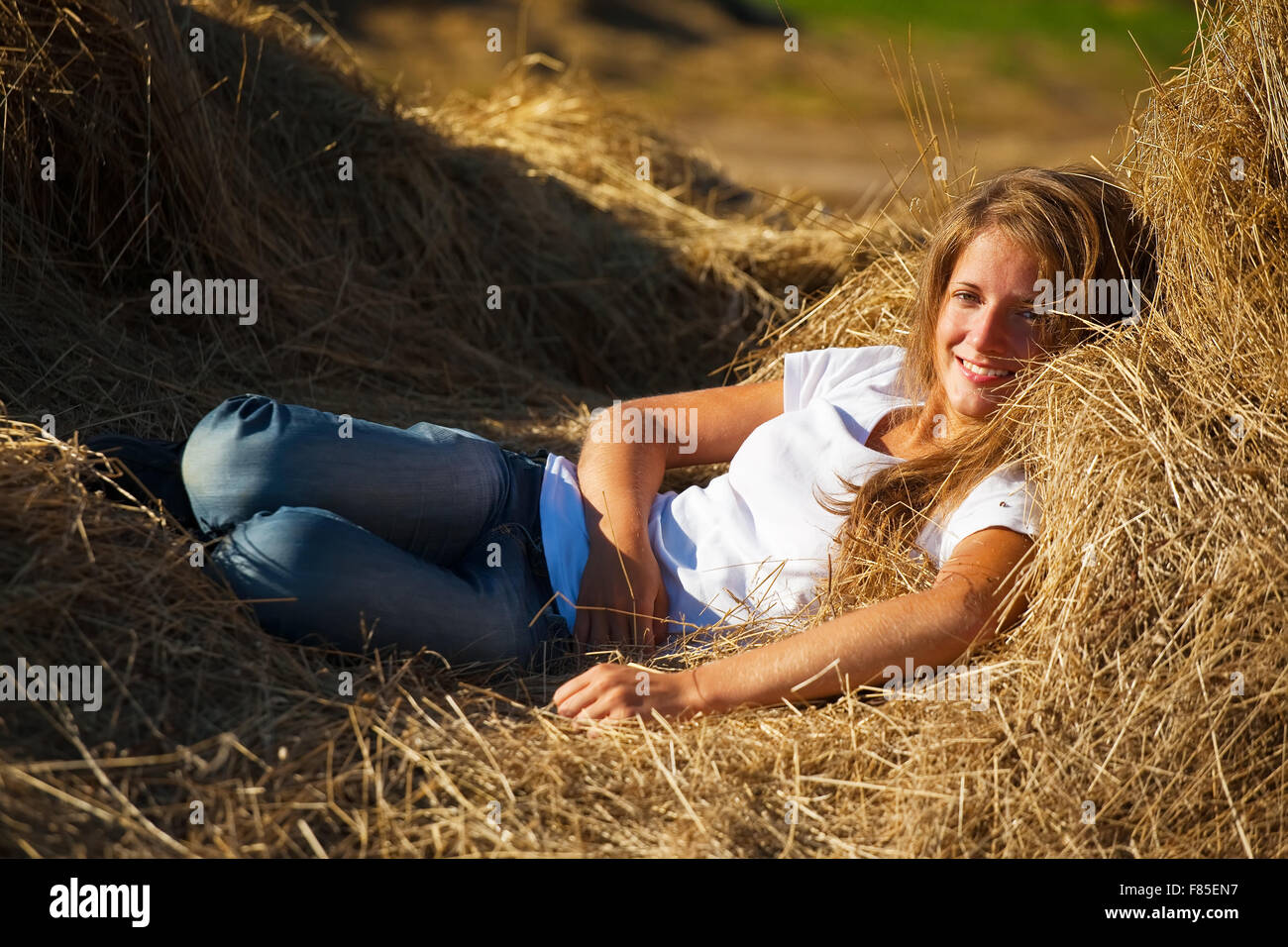 Pretty girl resting on fresh hay bale Stock Photo - Alamy