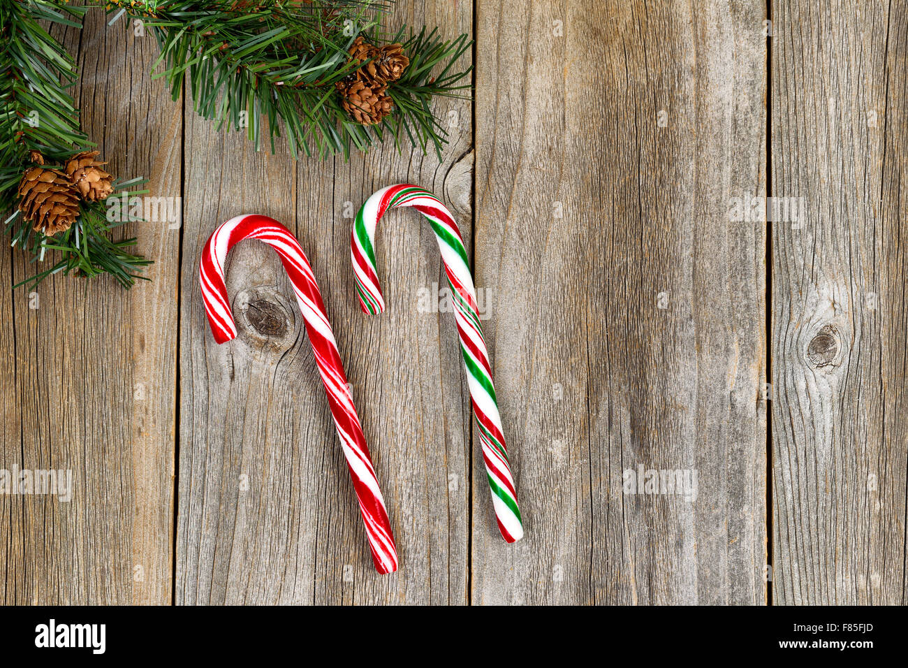 Large candy canes with evergreen setting on rustic wood. High angled