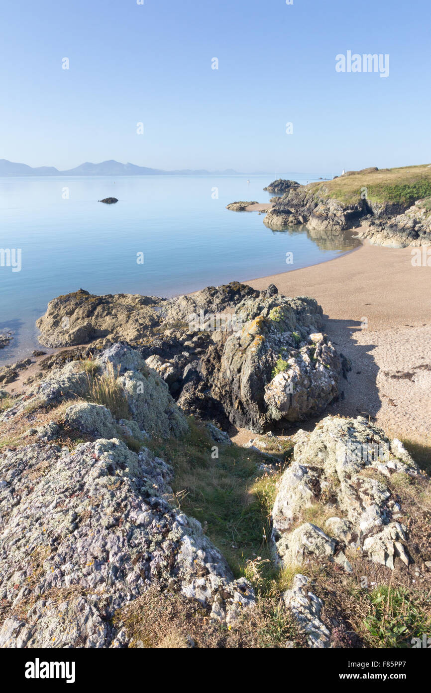 Volcanic rock and beach on Llanddwyn Island, Anglesey, Wales with the Llyn peninsula in the background Stock Photo