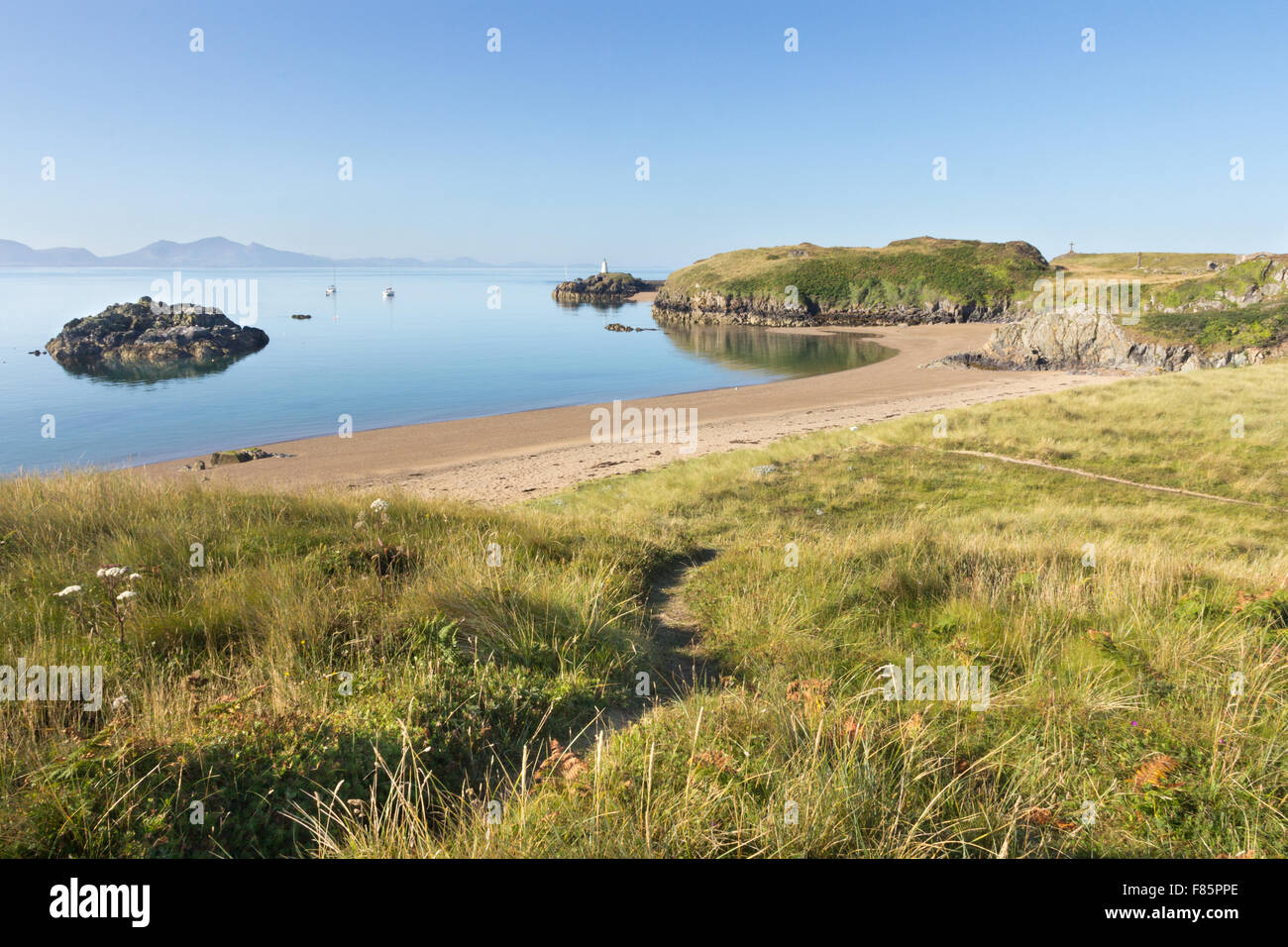 Beach on Llanddwyn Island, Anglesey with the lighhouse in the background and the Llyn peninsula in the distance Stock Photo