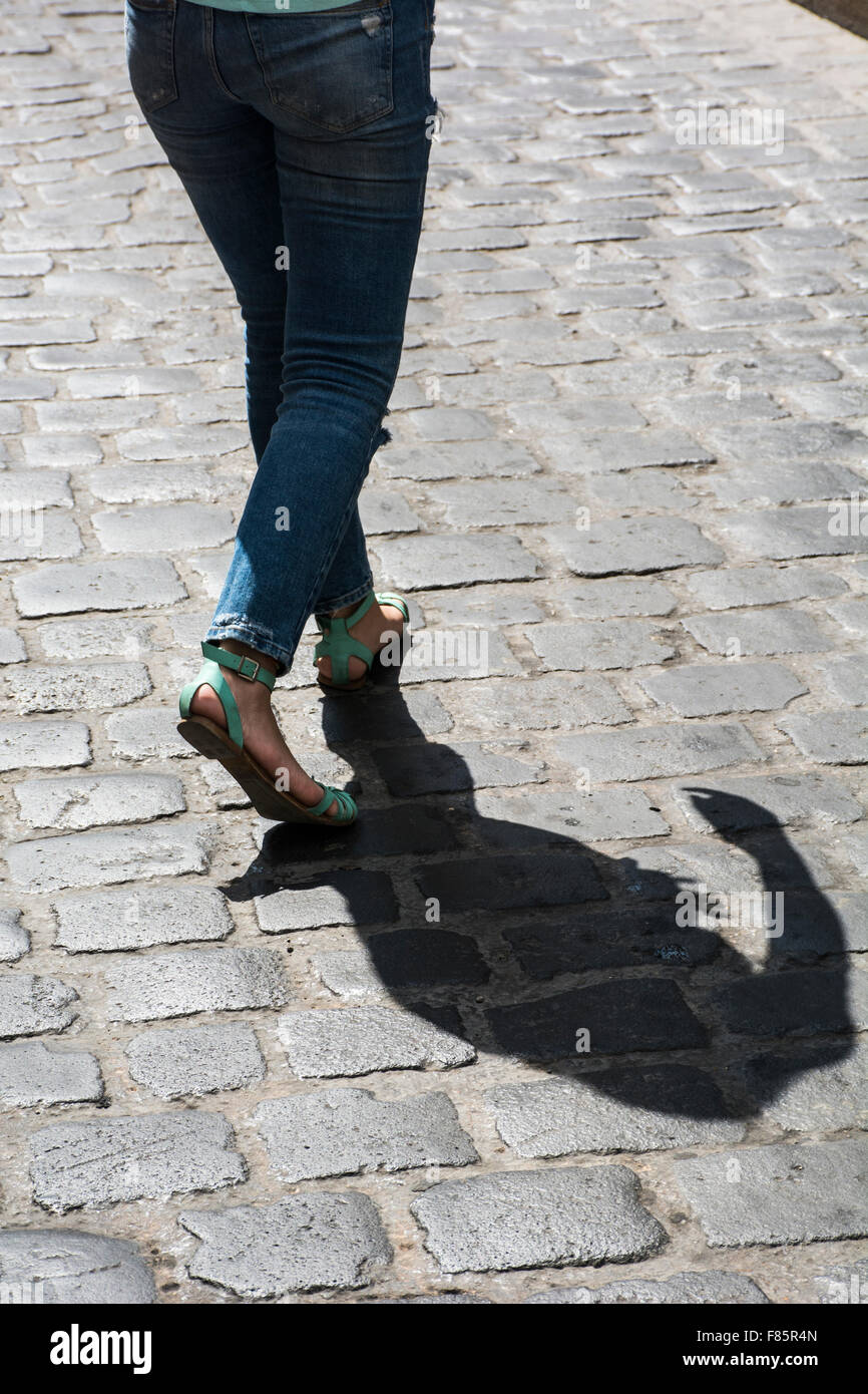 Close up of a young woman walking on a cobbled road Stock Photo