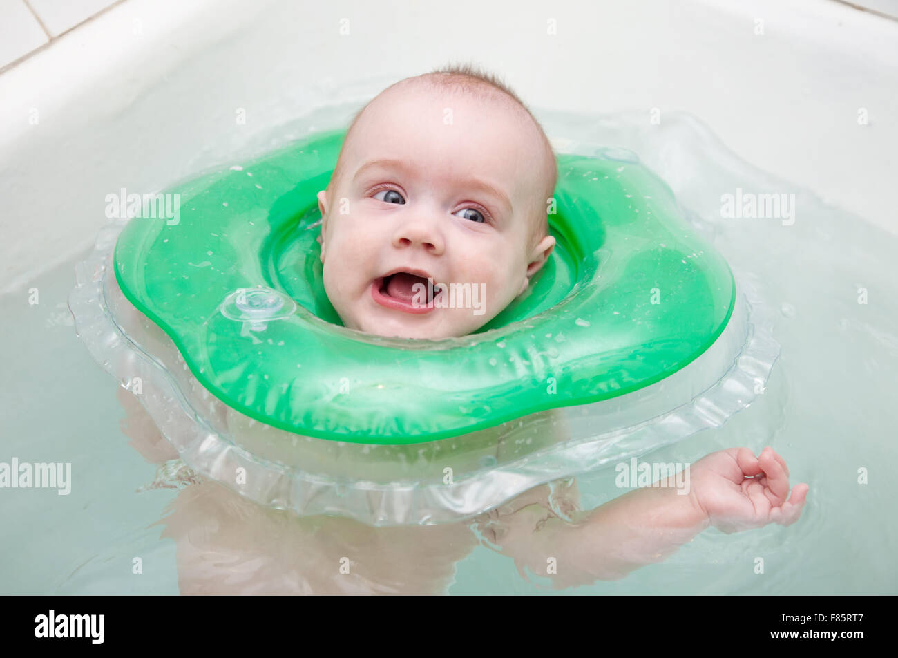 Six month baby swimming with neck swim ring in bath Stock Photo Alamy