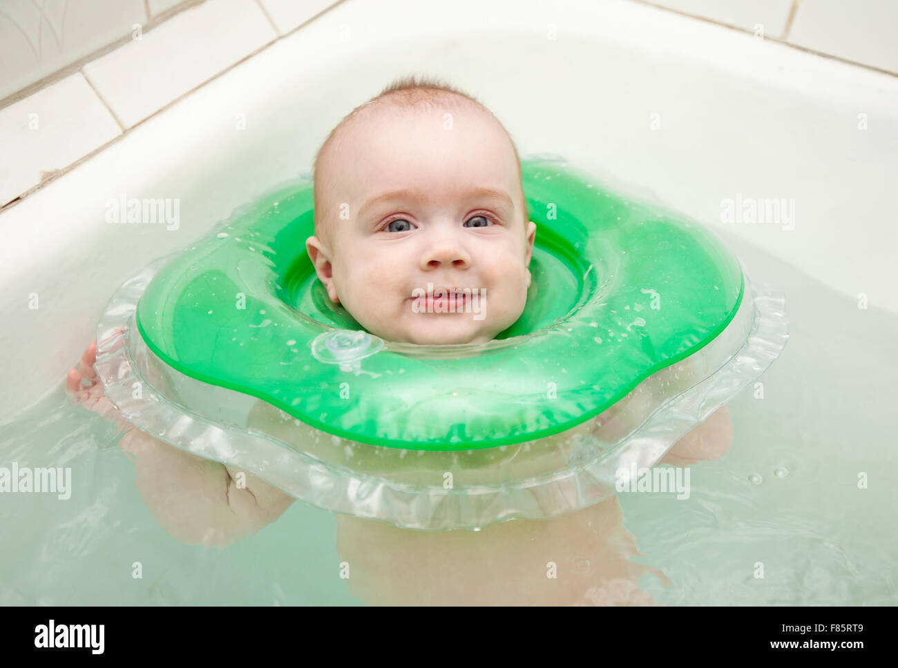 Six month baby swimming with neck swim ring in bath Stock Photo Alamy