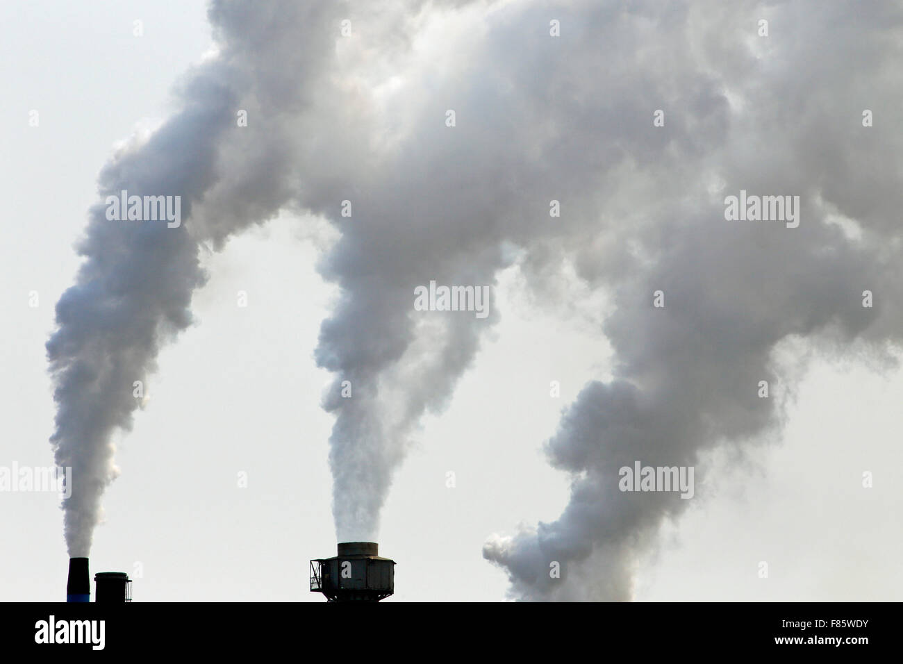 Smoke stacks from a factory spewing greenhouse gases and pollution into the air Stock Photo