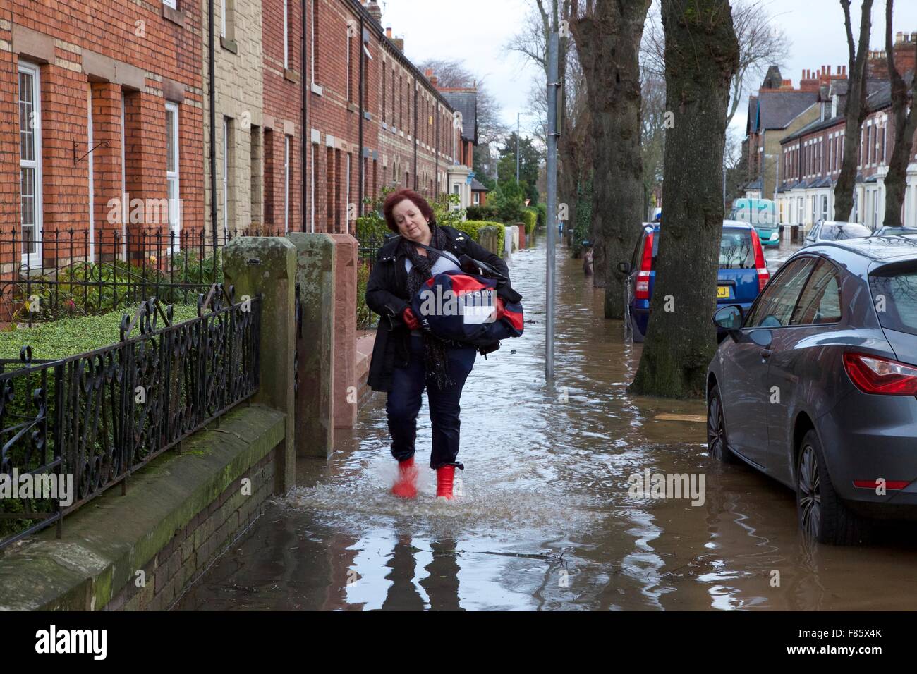 Cumbria Floods. 6th December 2015. Streets flooded. Woman wades out of flood waters with a few possessions. Flood waters catch residents unprepared  as their homes are inundated. Storm Desmond caused severe flooding in Carlisle and across Cumbria. Carlisle, Cumbria, England, UK. Credit:  Andrew Findlay/Alamy Live News Stock Photo