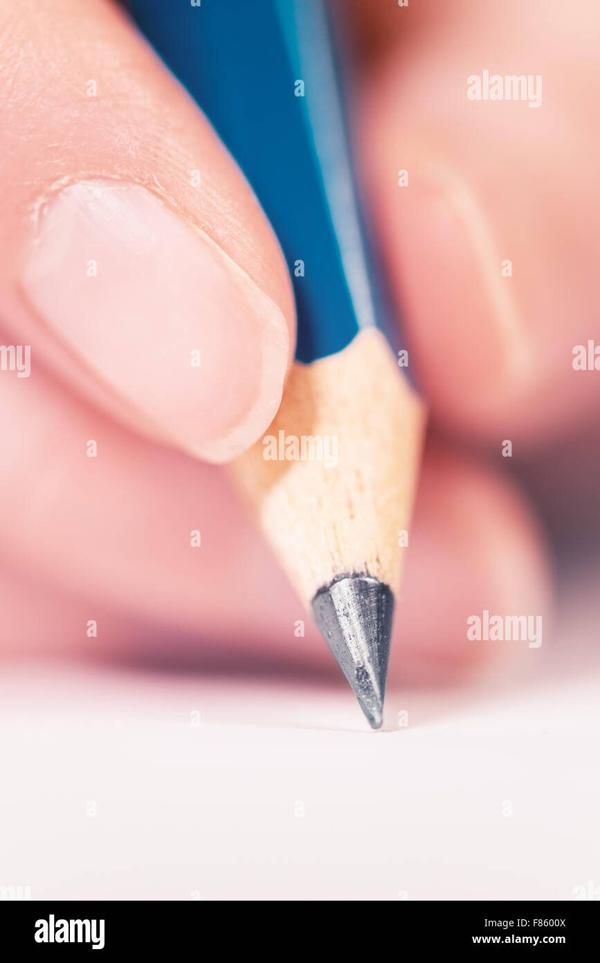 Macro shot of male hand writing notes with pencil on a piece of paper, selective focus Stock Photo