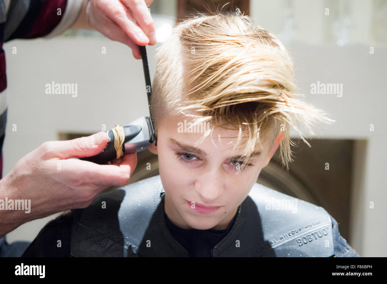 A blond boy has his hair cut Stock Photo