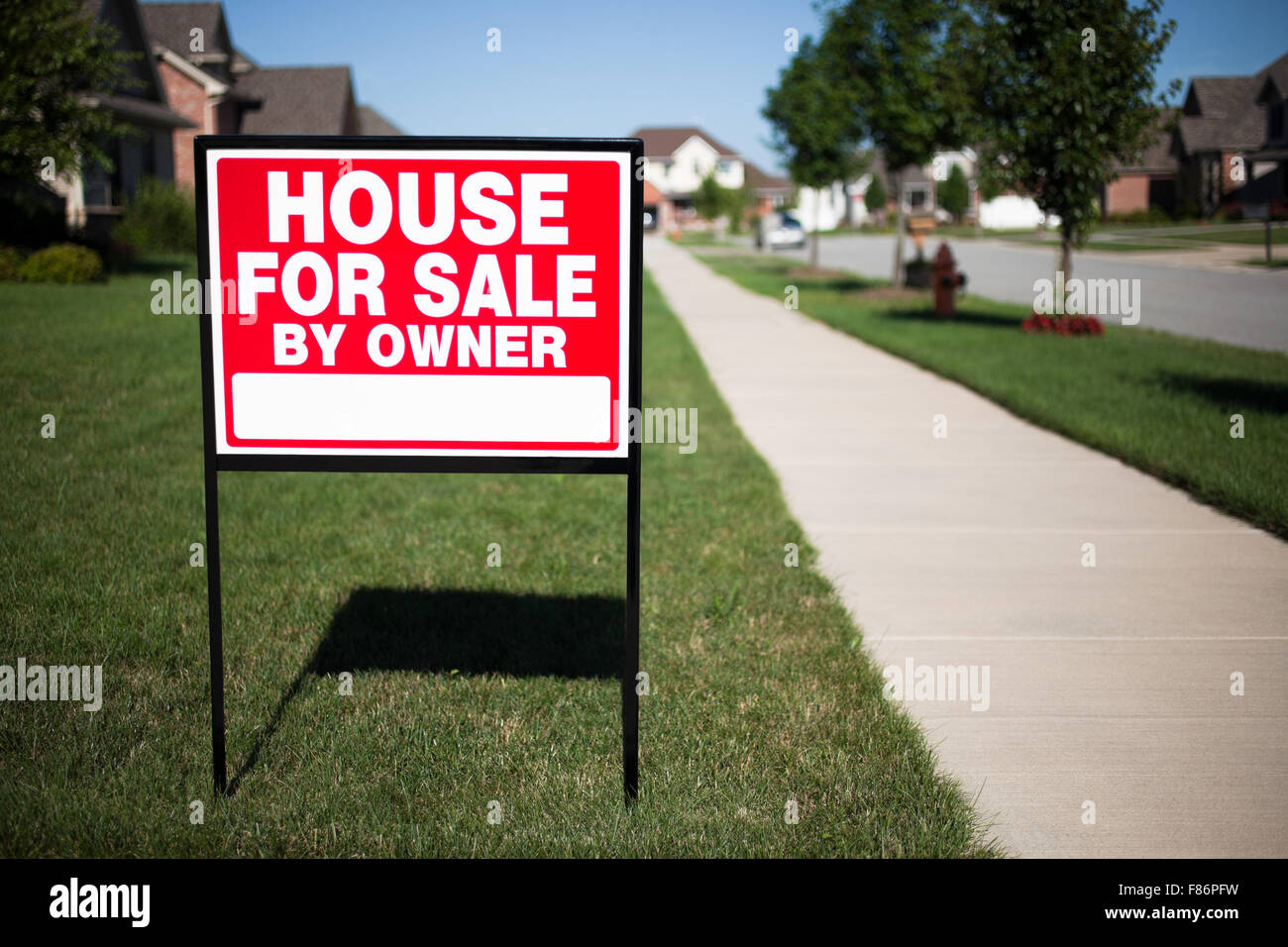 House For Sale By Owner Sign in a front yard of a home Stock Photo