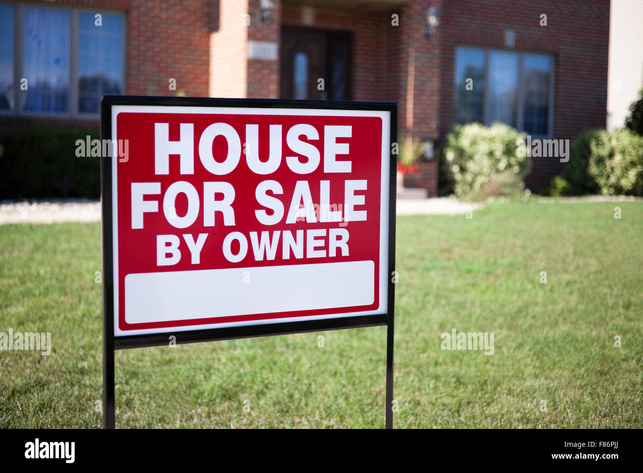 House For Sale By Owner Sign in a front yard of a house Stock Photo