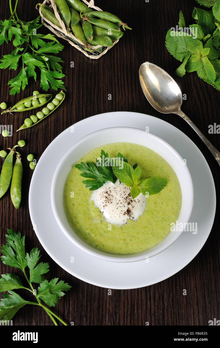 Portion cream soup with green peas with mint cream Stock Photo